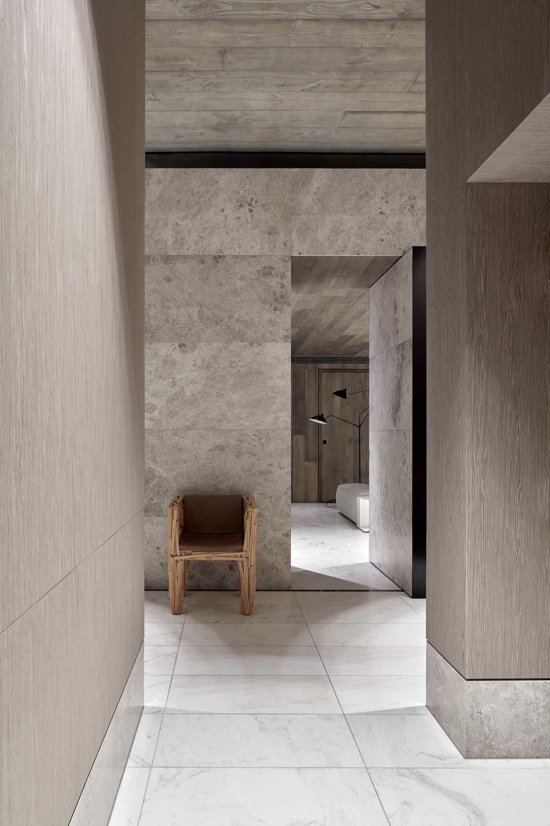 A modern entryway with marble flooring and a mix of concrete and wood materials.