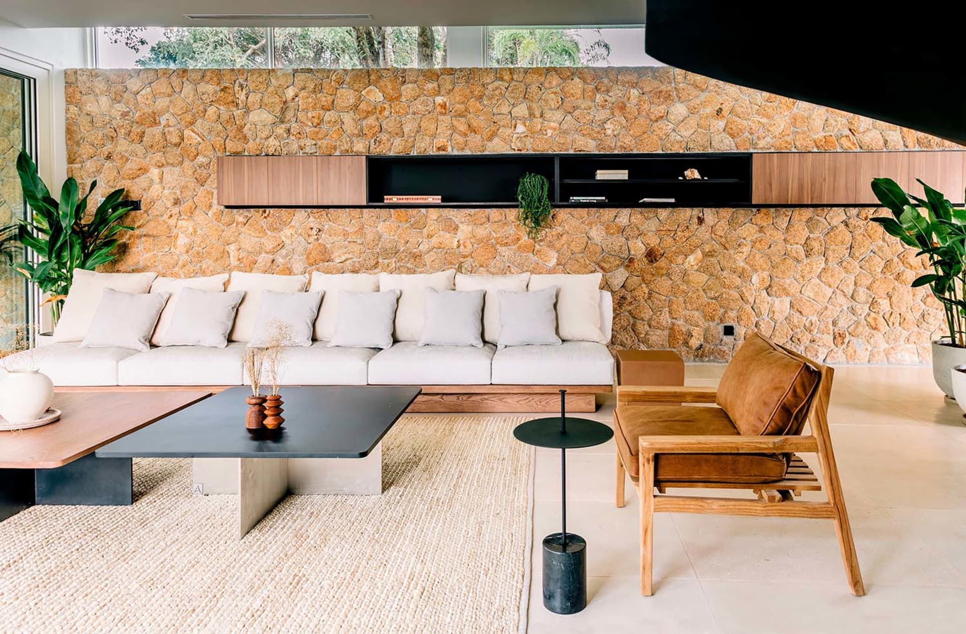 Modern living room with stone accent wall, white sofa, wooden armchair, and metal coffee table.