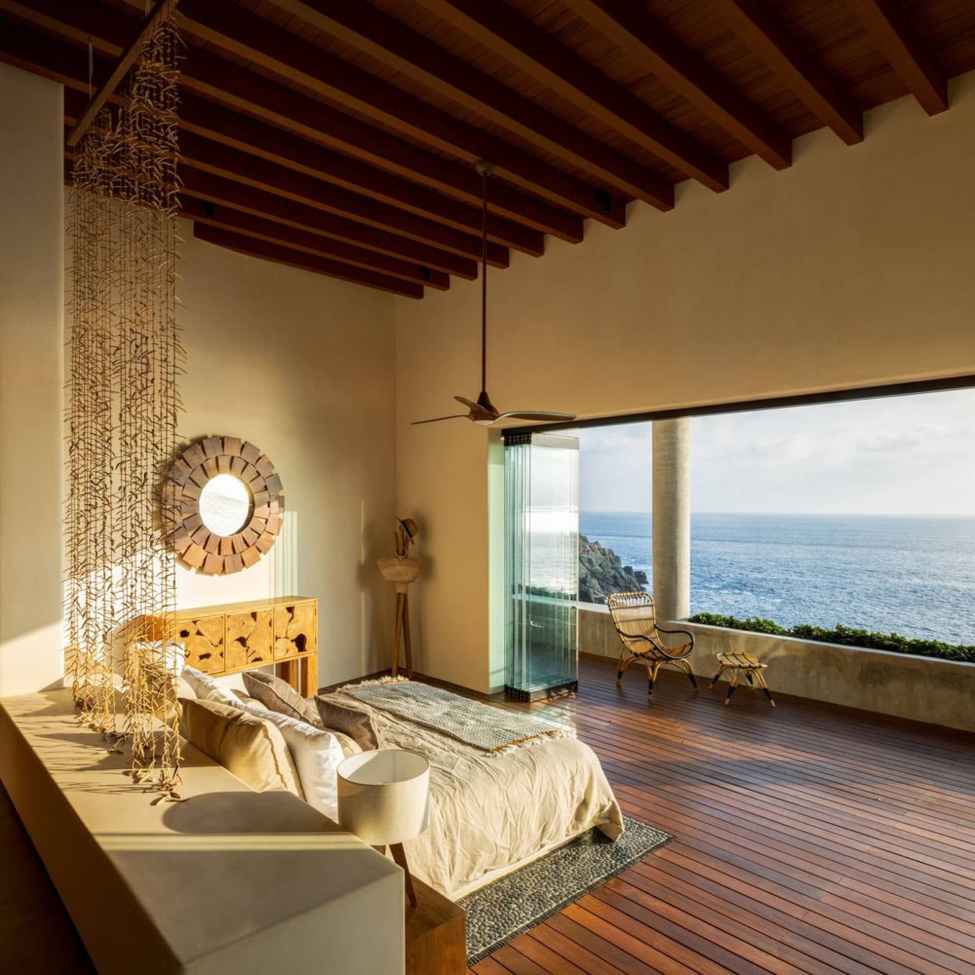 Modern residential bedroom with wooden floors and a view of the ocean.