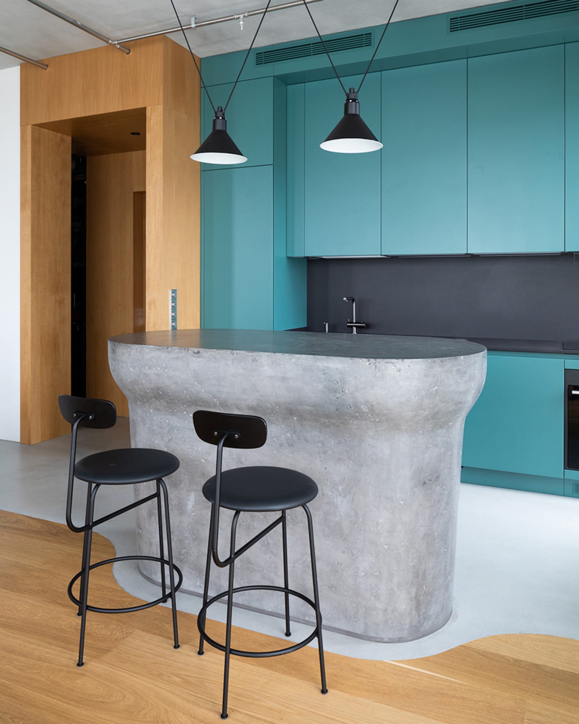Modern kitchen features a concrete countertop and wooden cabinets.
