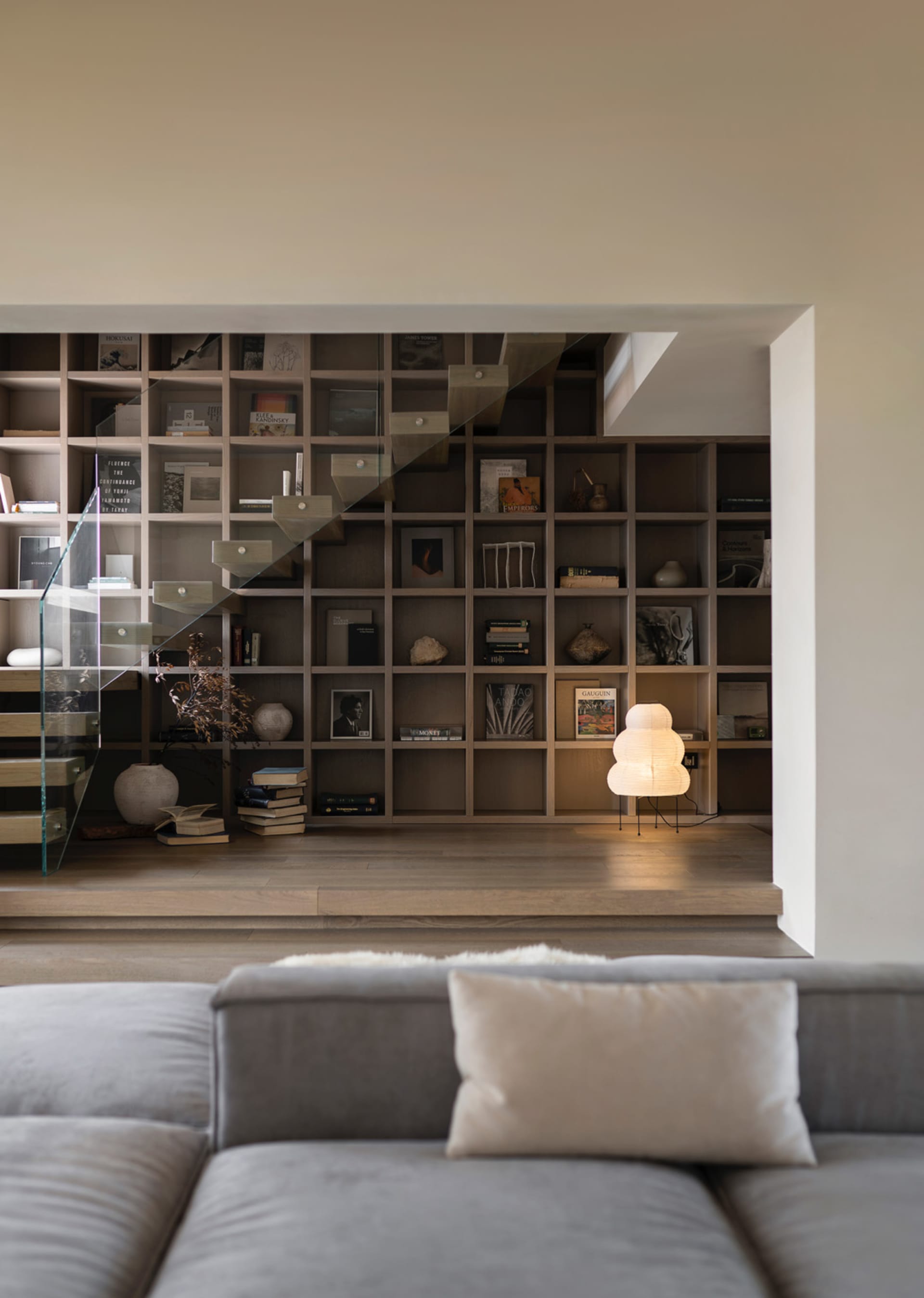 A modern living room featuring a wooden bookshelf with books and decorative items.