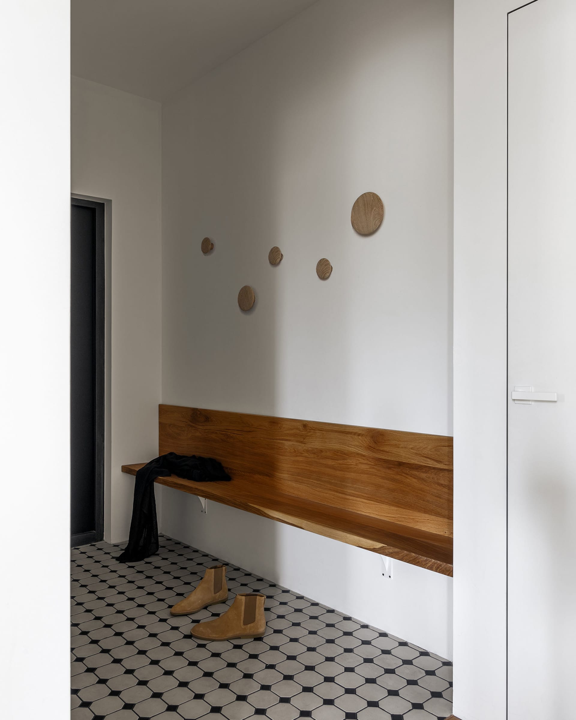 Entryway featuring a minimalist design with a wooden bench and ceramic tiles