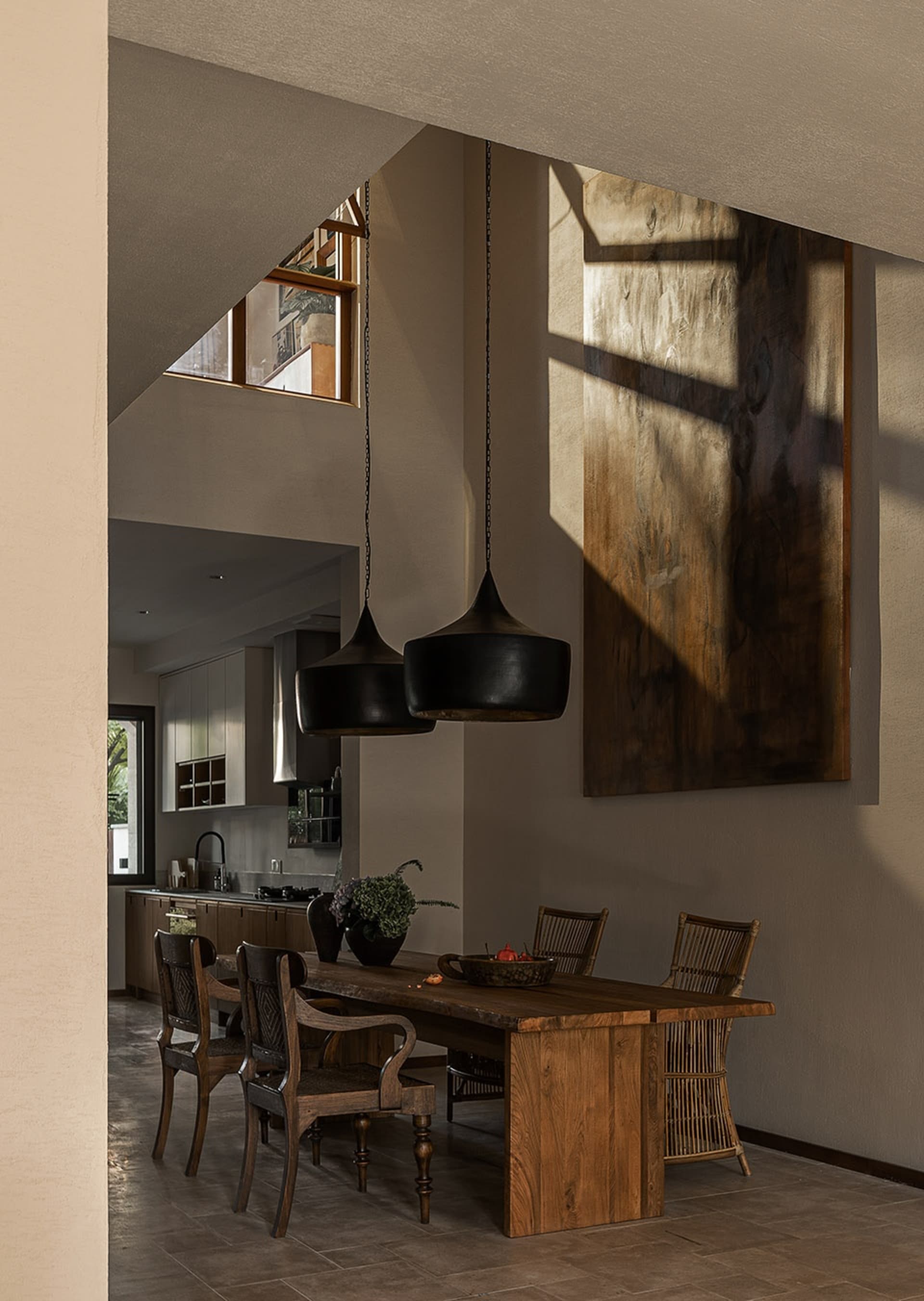 Modern dining room featuring wooden furniture, pendant lights, and a large abstract painting.