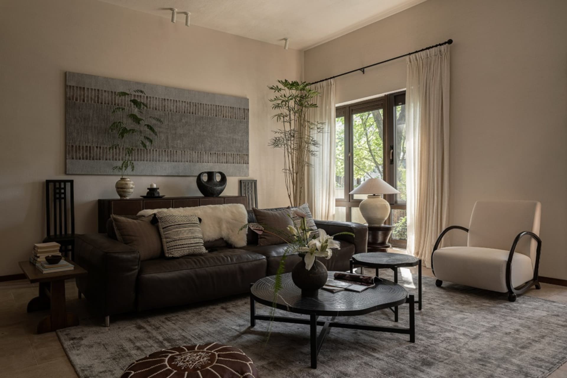 Modern living room featuring a cozy couch with accent pillows, a round coffee table, and natural light through a large window