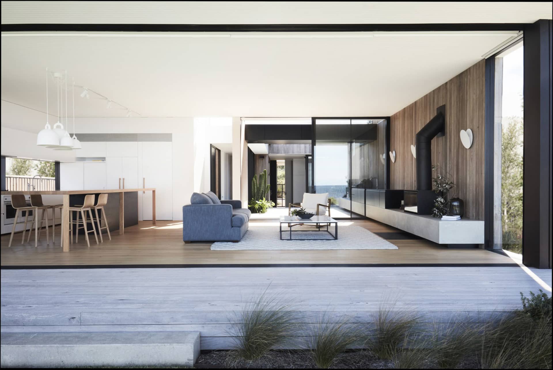 A modern living room featuring a wooden floor, a grey sofa, a white armchair, and a coffee table.