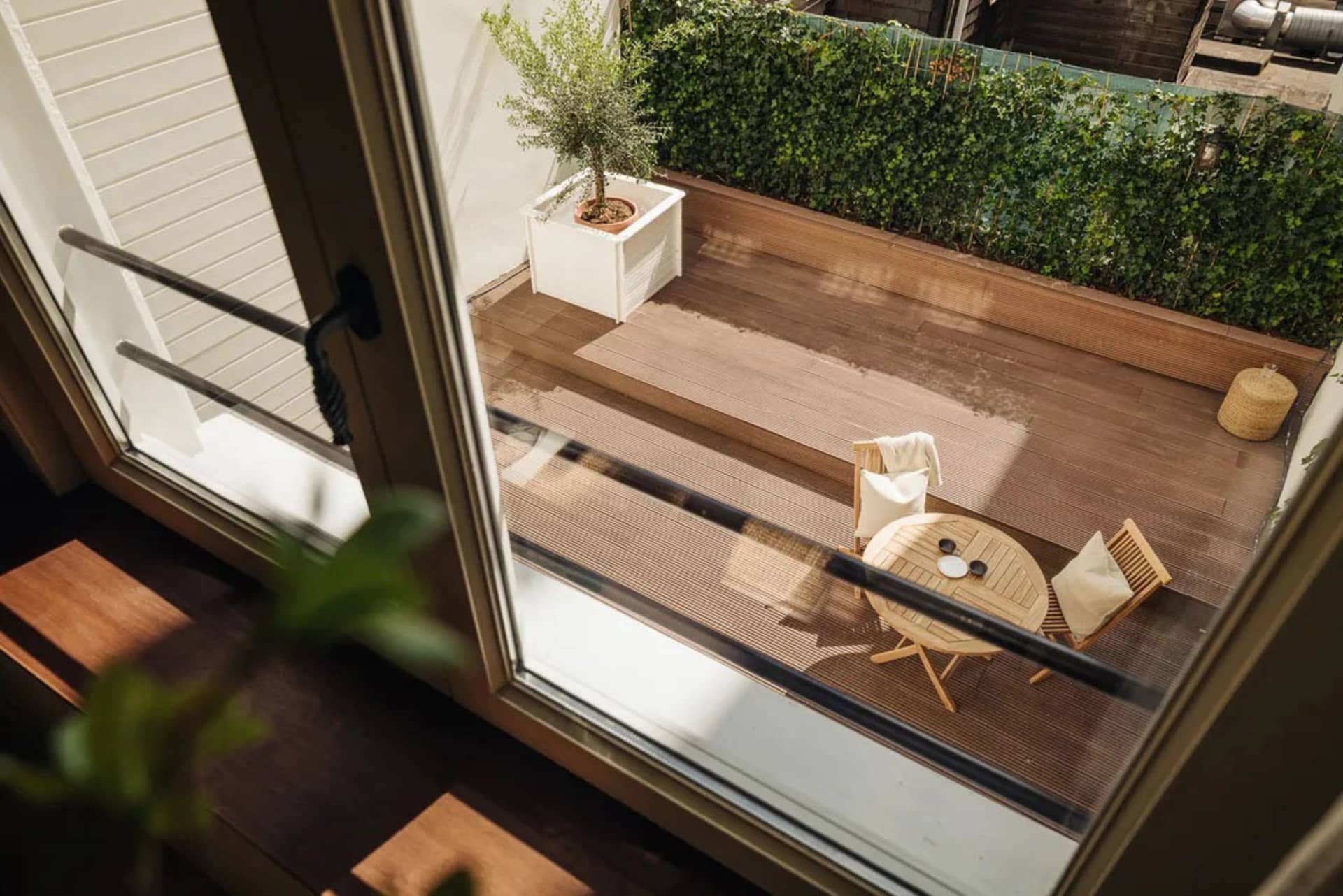 Modern porch features a wooden table with chairs and a potted plant.