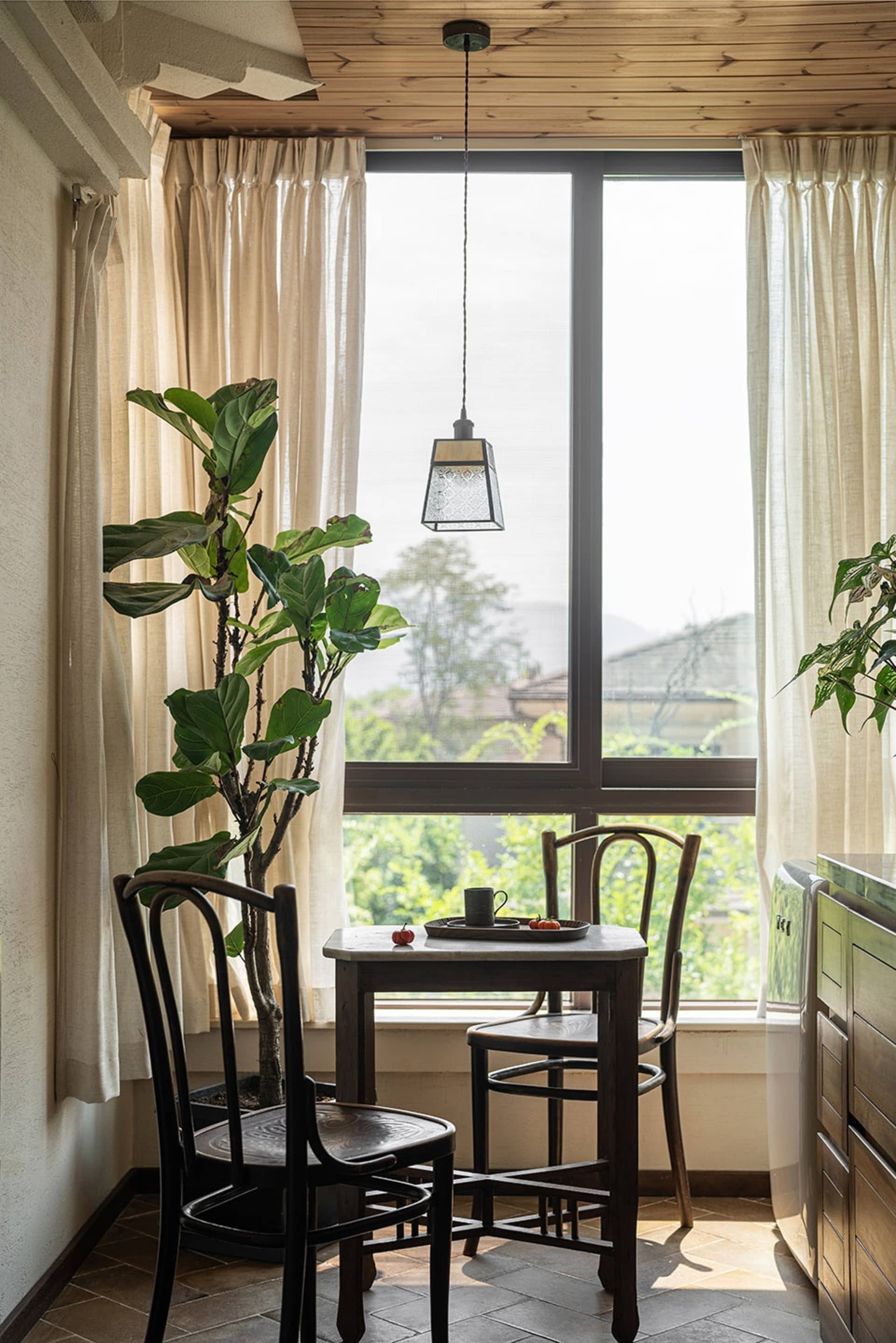 A modern wooden kitchen with large windows showcasing a serene view of nature.