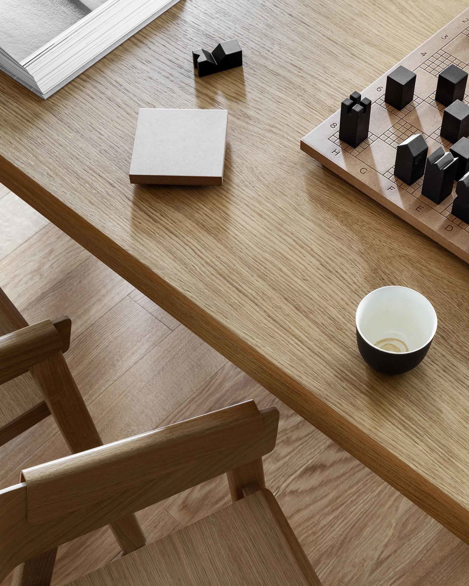 Wooden interior with a tutorial book, coffee cup, and chessboard.