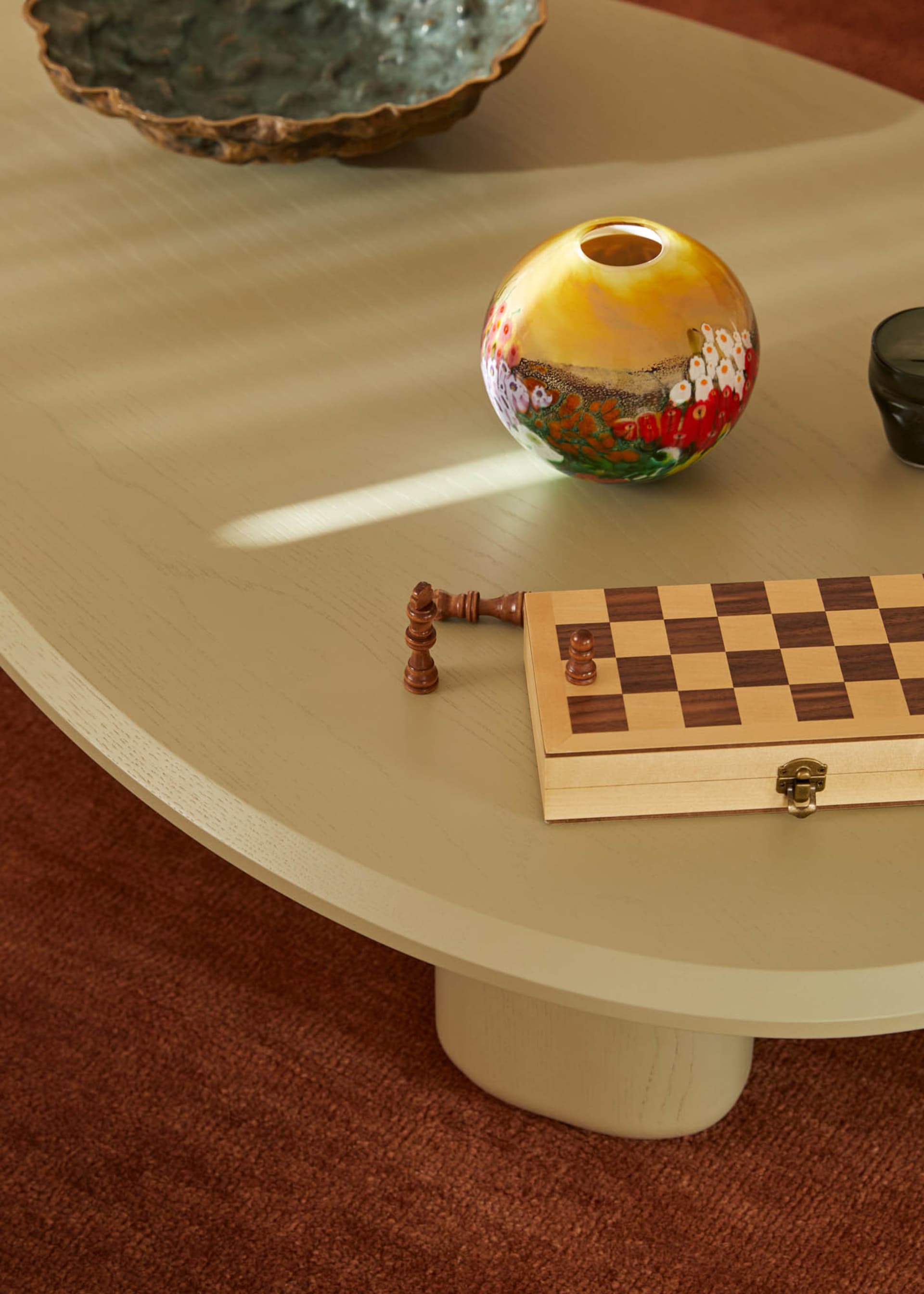 A wooden chessboard and vase on a coffee table.