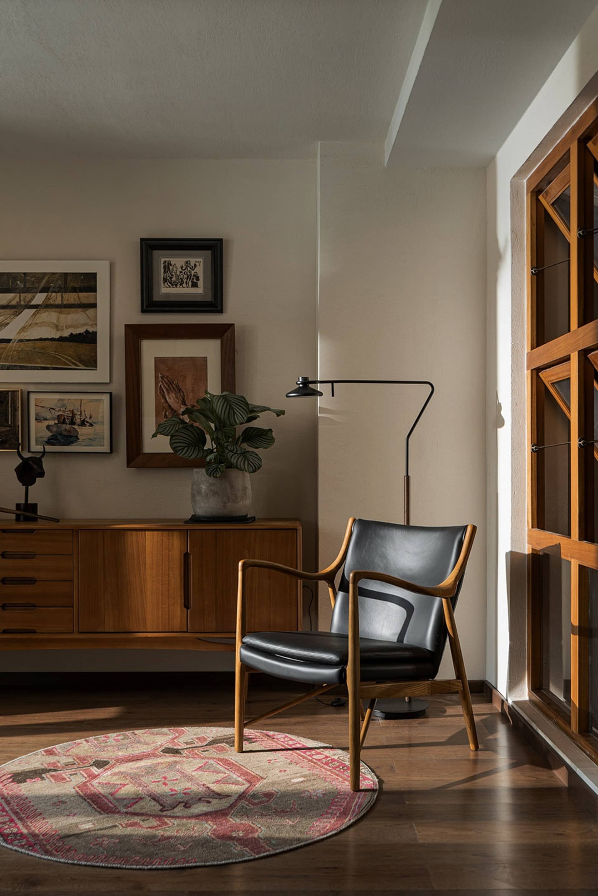 A cozy mid-century modern living room with wood, leather, and glass elements.