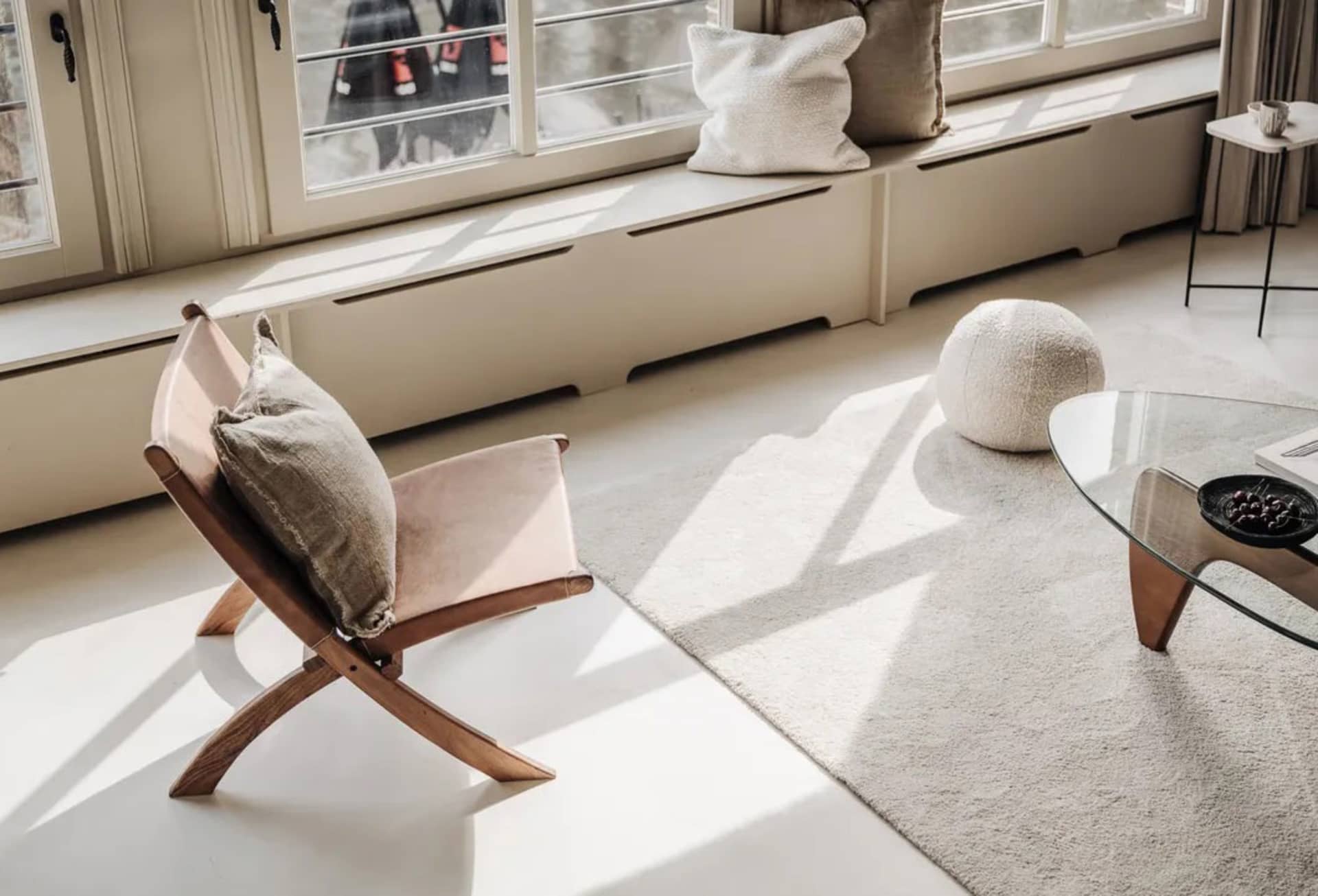 A minimalist interior design featuring a wooden chair with pillows on a white floor.