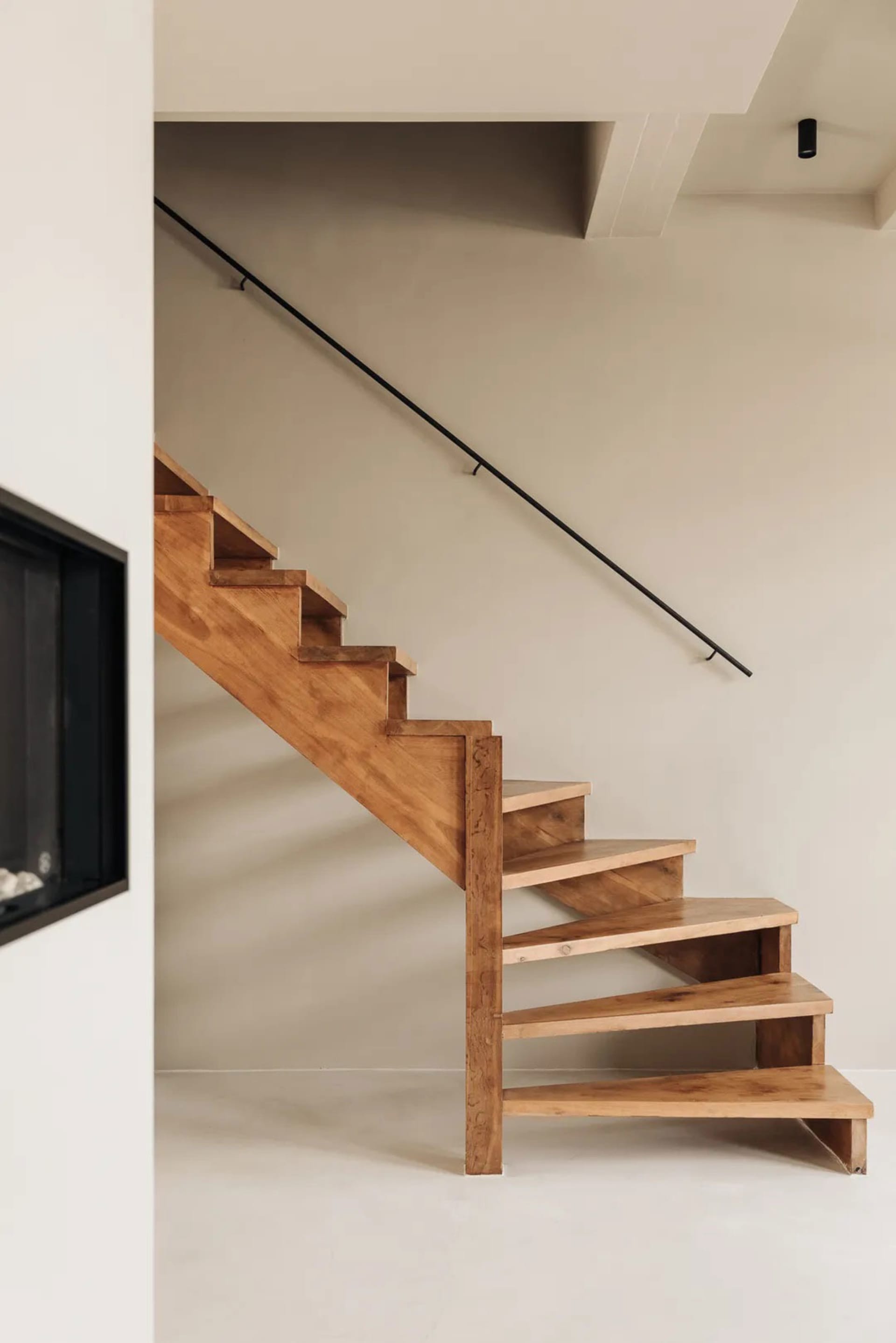 A minimalist wooden staircase with black handrail in a modern interior