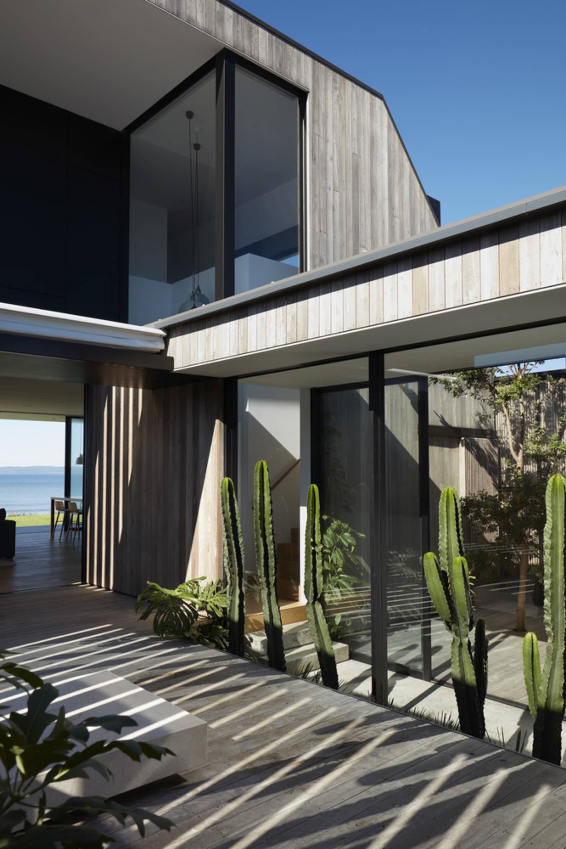 Modern house exterior with wooden veranda and large windows.