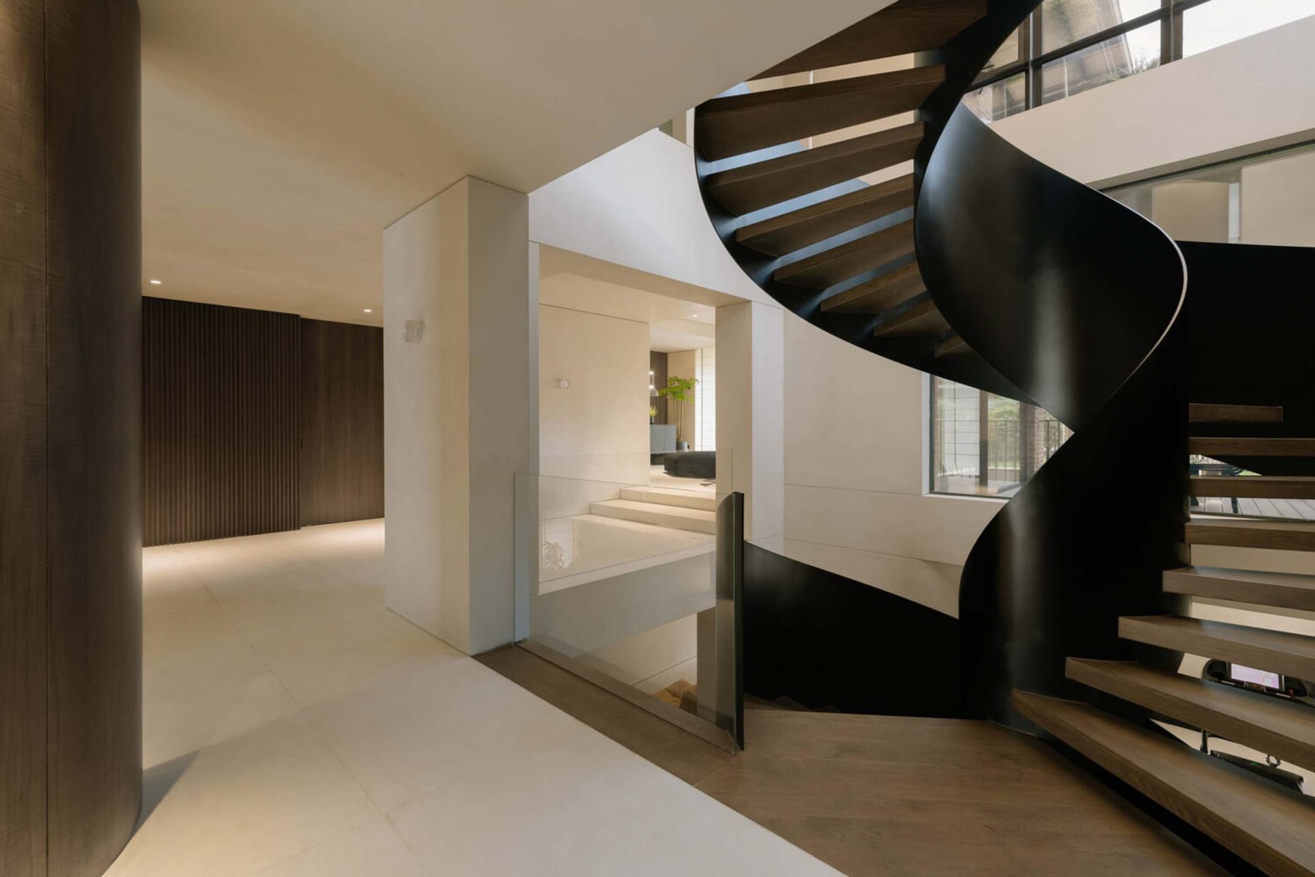 A modern interior design featuring a black metal spiral staircase.