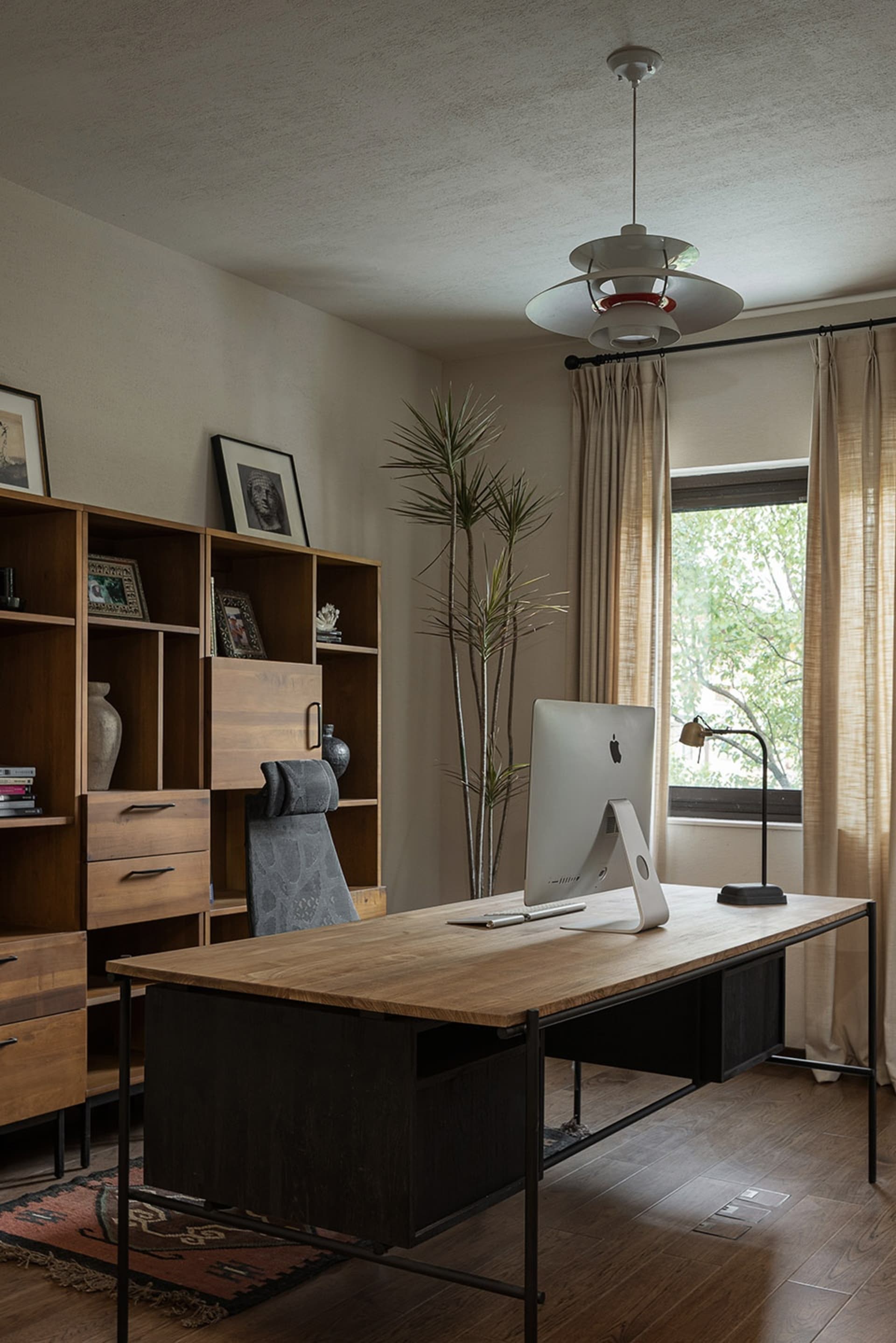 Modern industrial-style home office featuring a wooden desk, chair, and bookshelf with decor items.