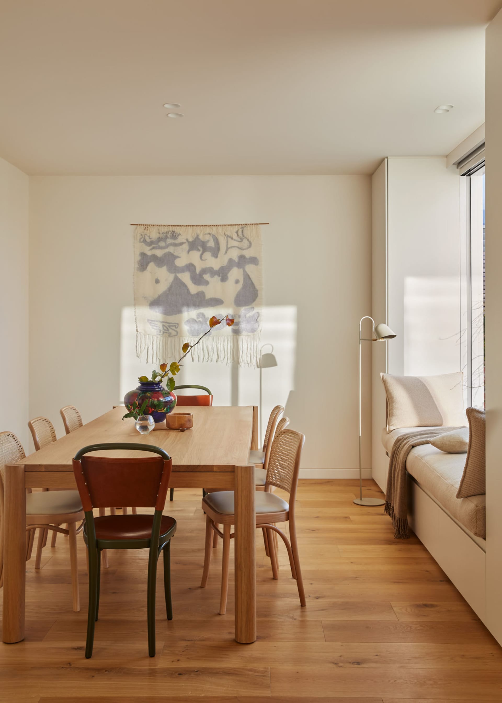 A minimalist dining room featuring a wooden table and chairs.