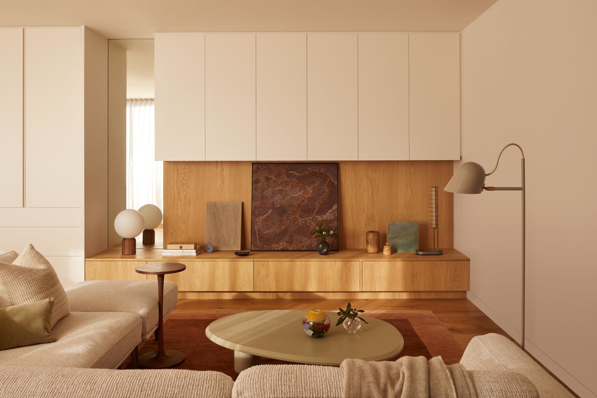 A minimalist living room featuring wood, leather, glass, and metal elements.