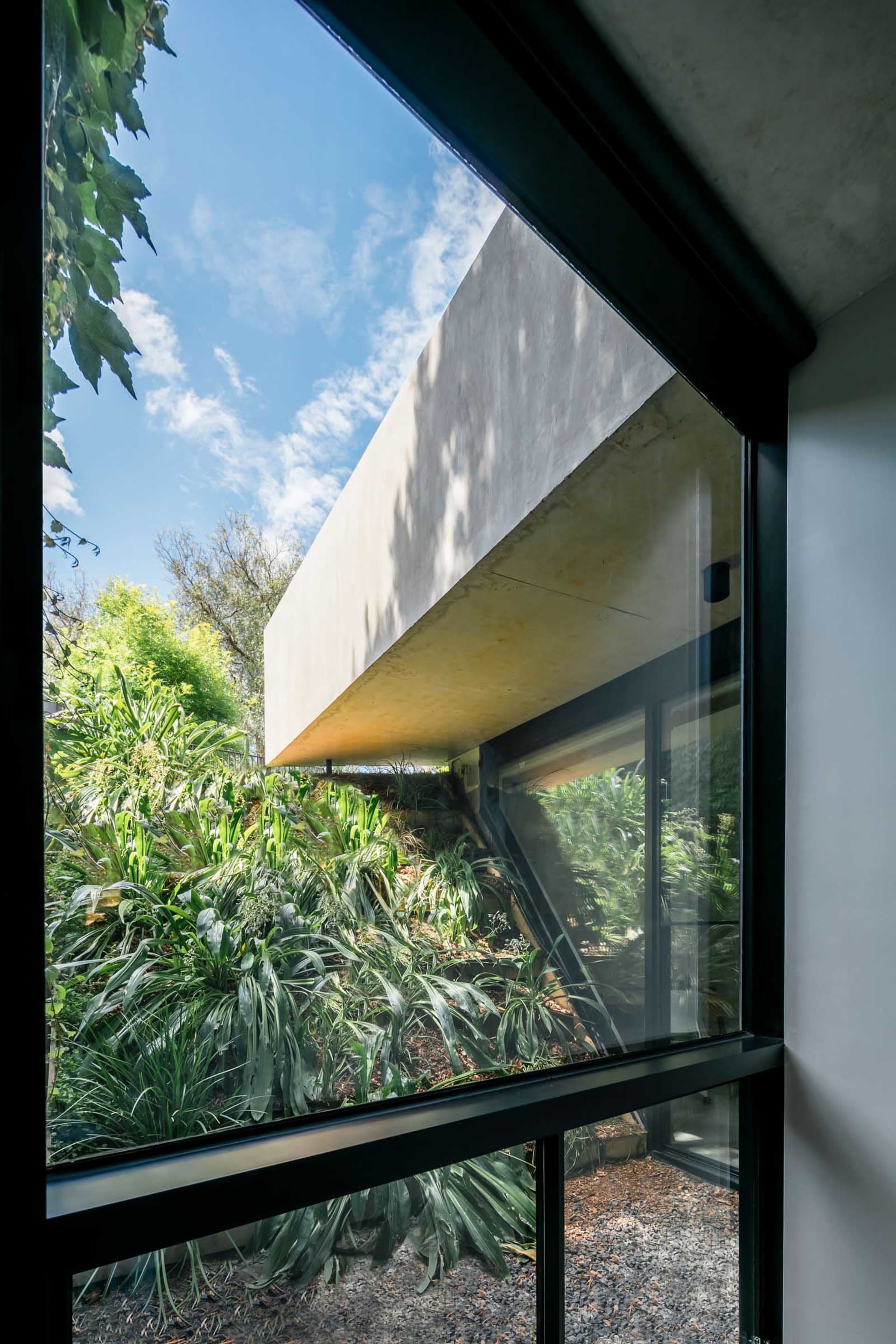 An architectural view showing a modern exterior with a combination of concrete and glass materials, seen through a window.