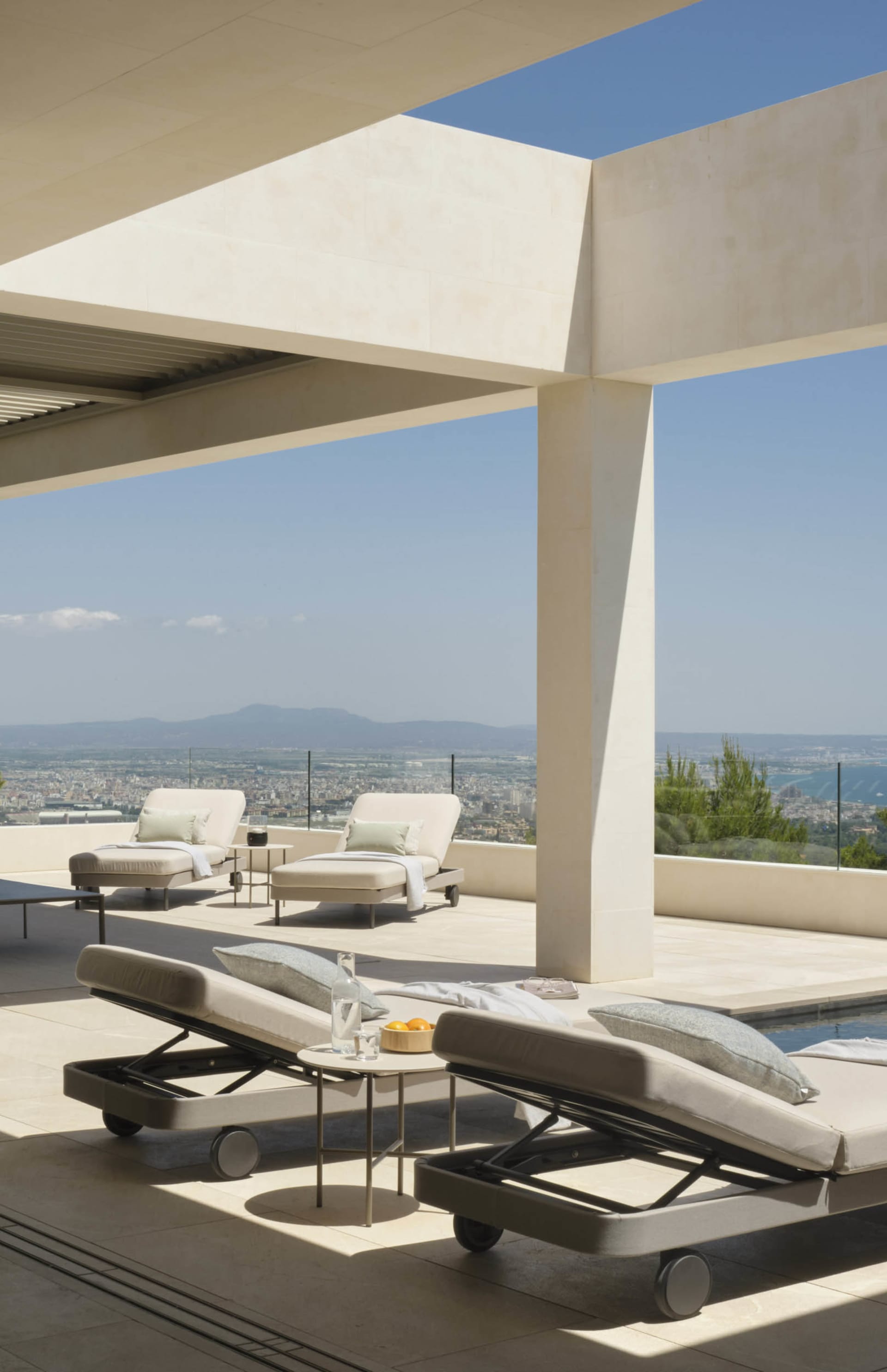 A modern, minimalist patio area featuring concrete surfaces and furniture.