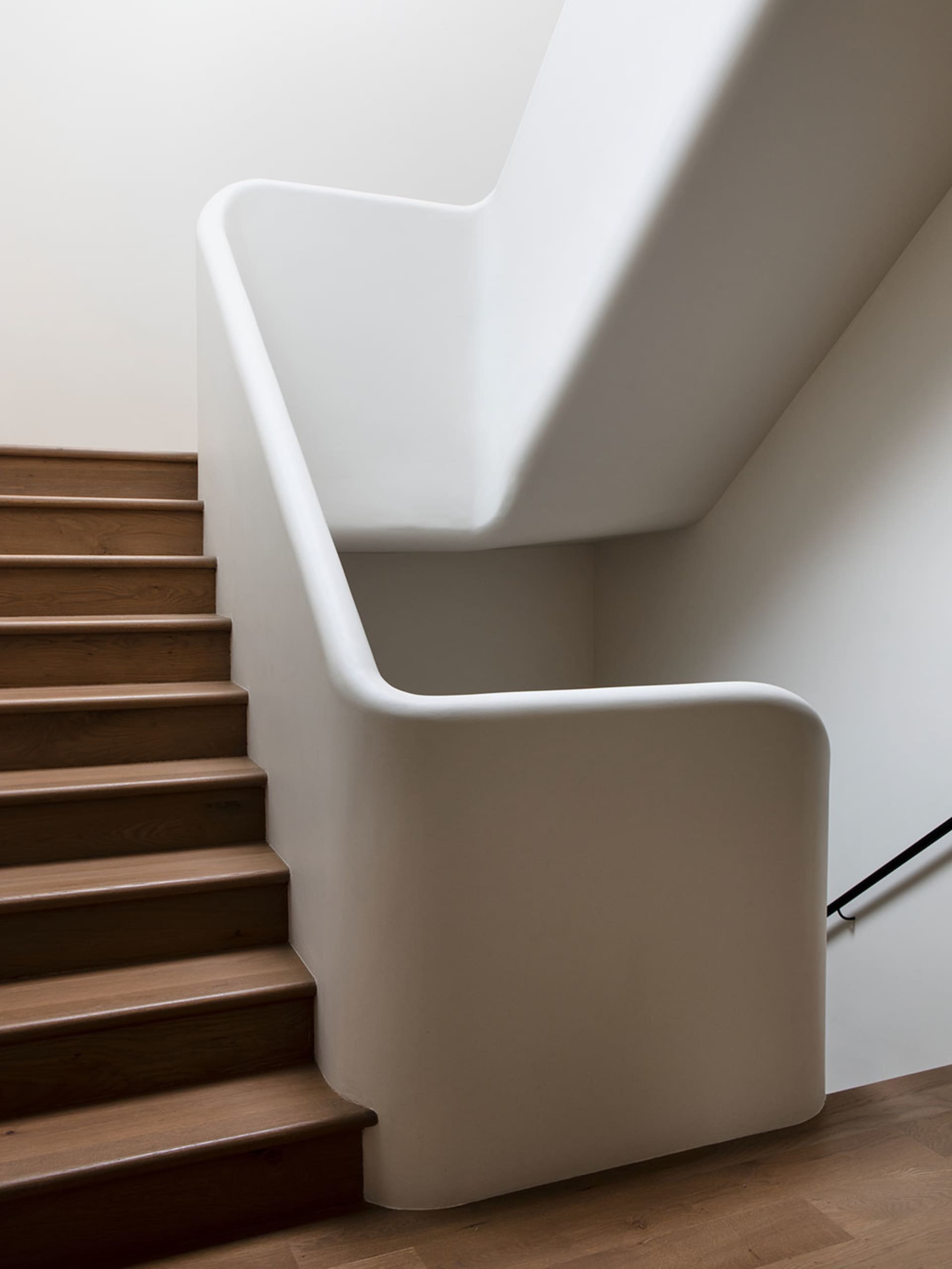 Modern interior staircase with concrete steps and wooden railings.