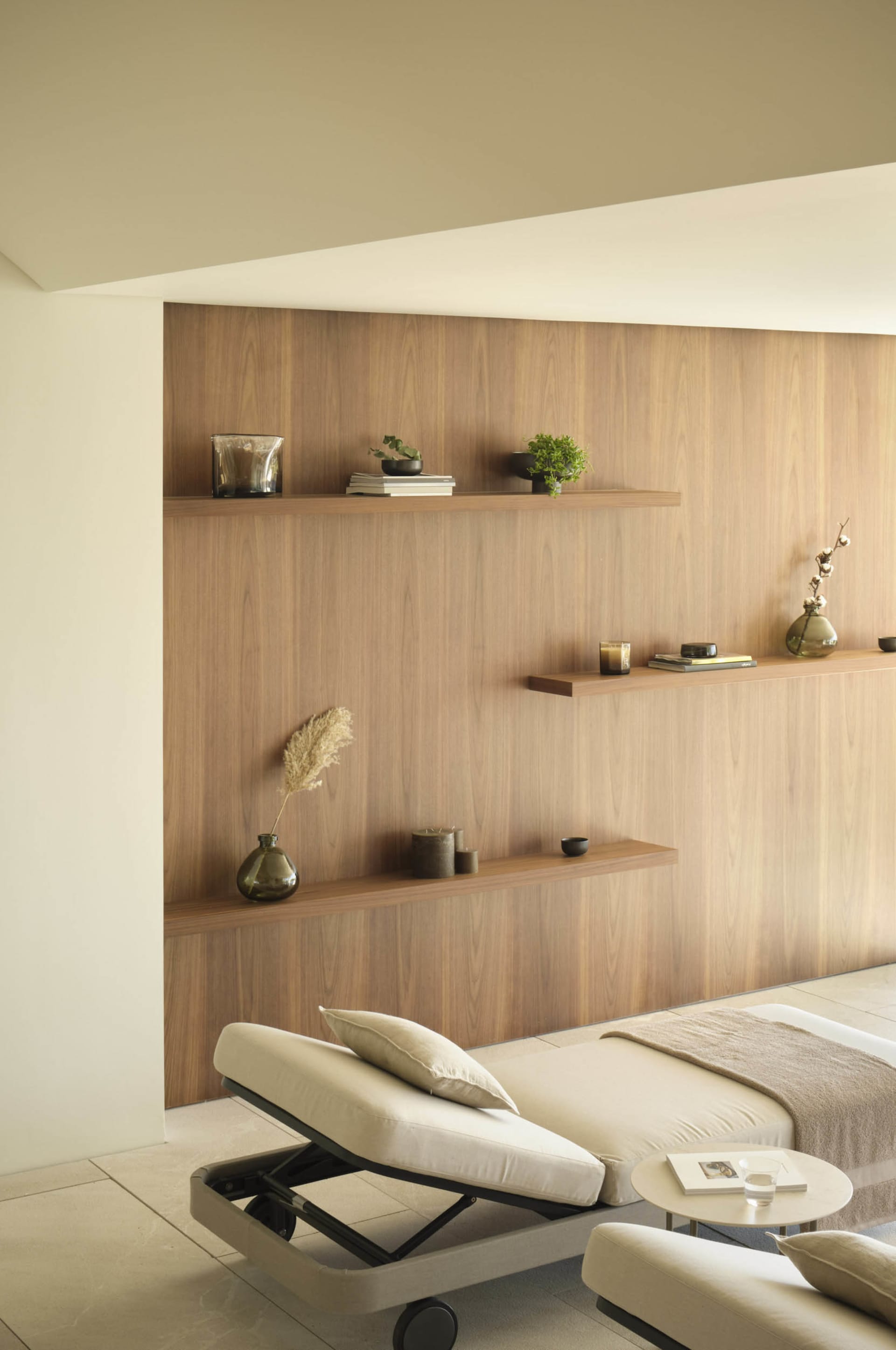 A modern living room with wooden accents, a chaise lounge, and floating shelves.