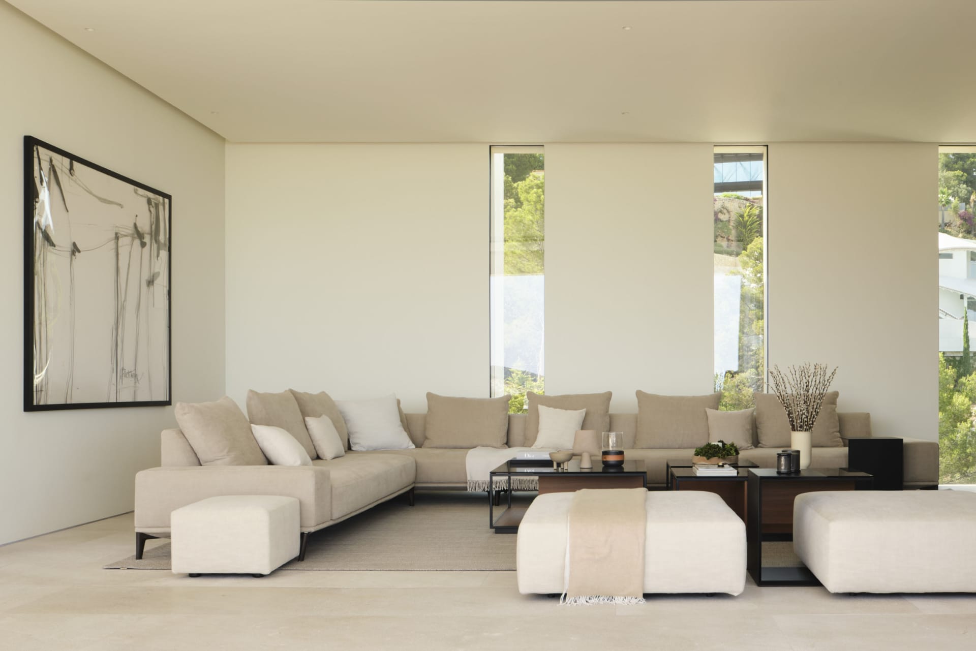 Modern minimalist living room with a large corner sofa, two ottomans, and a small coffee table.