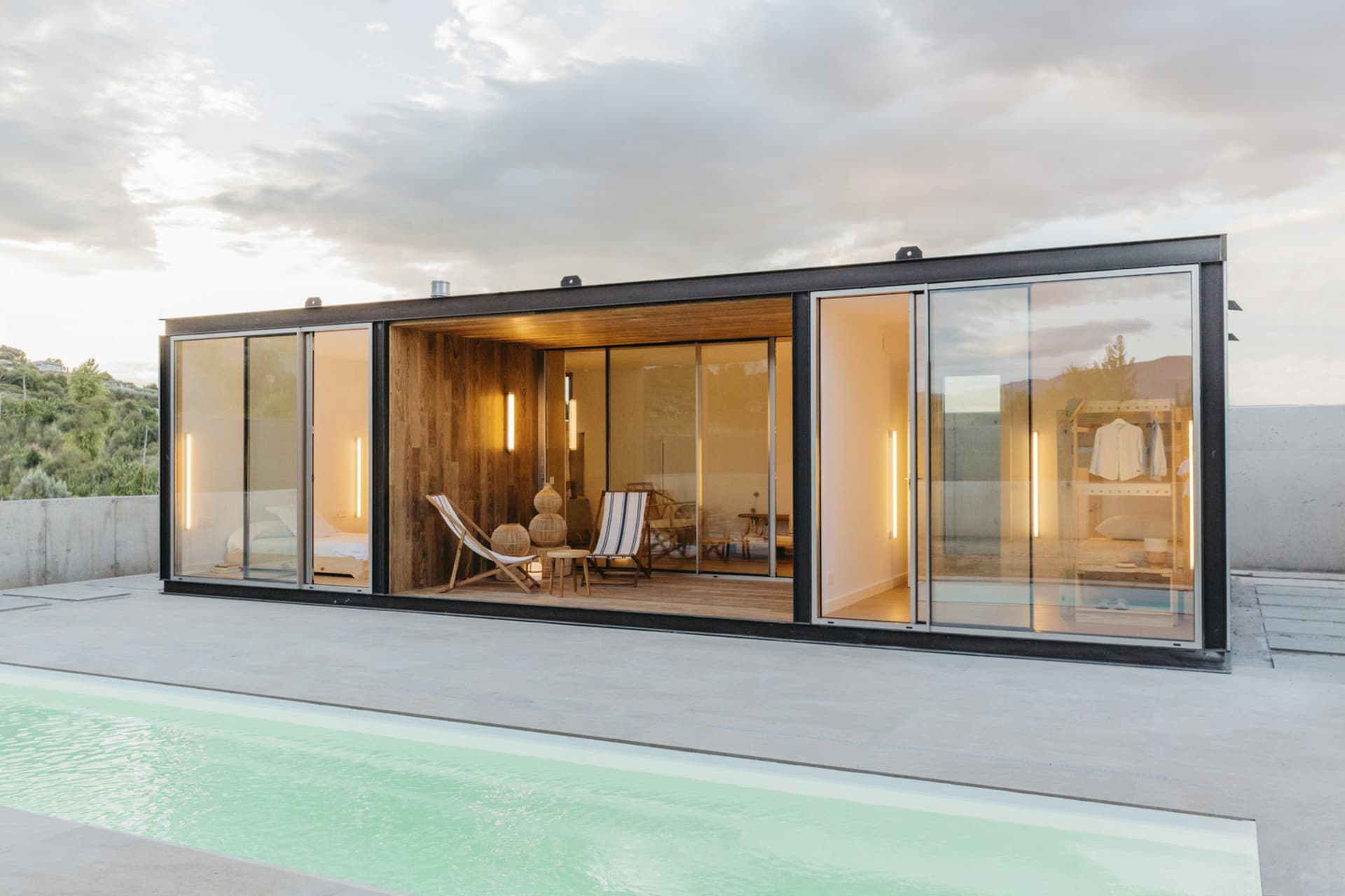 A modern residential exterior featuring glass and concrete materials.