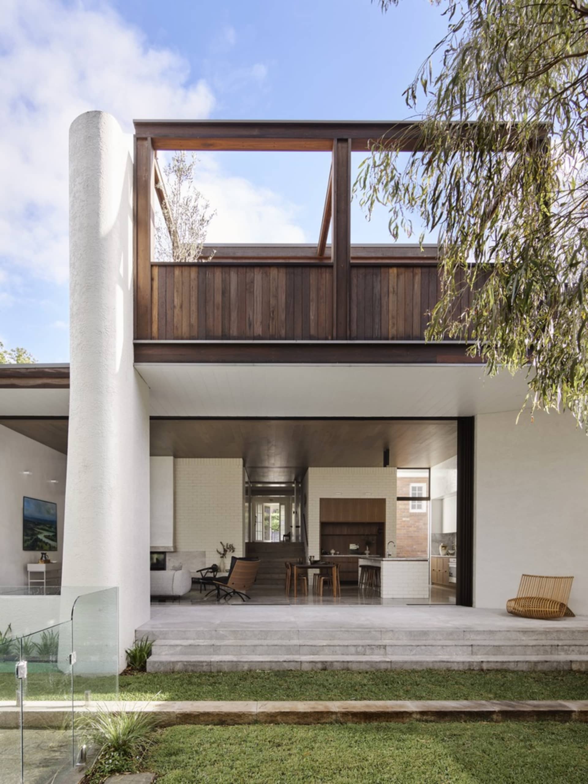 Modern residential building featuring large windows, wooden accents, and concrete steps.