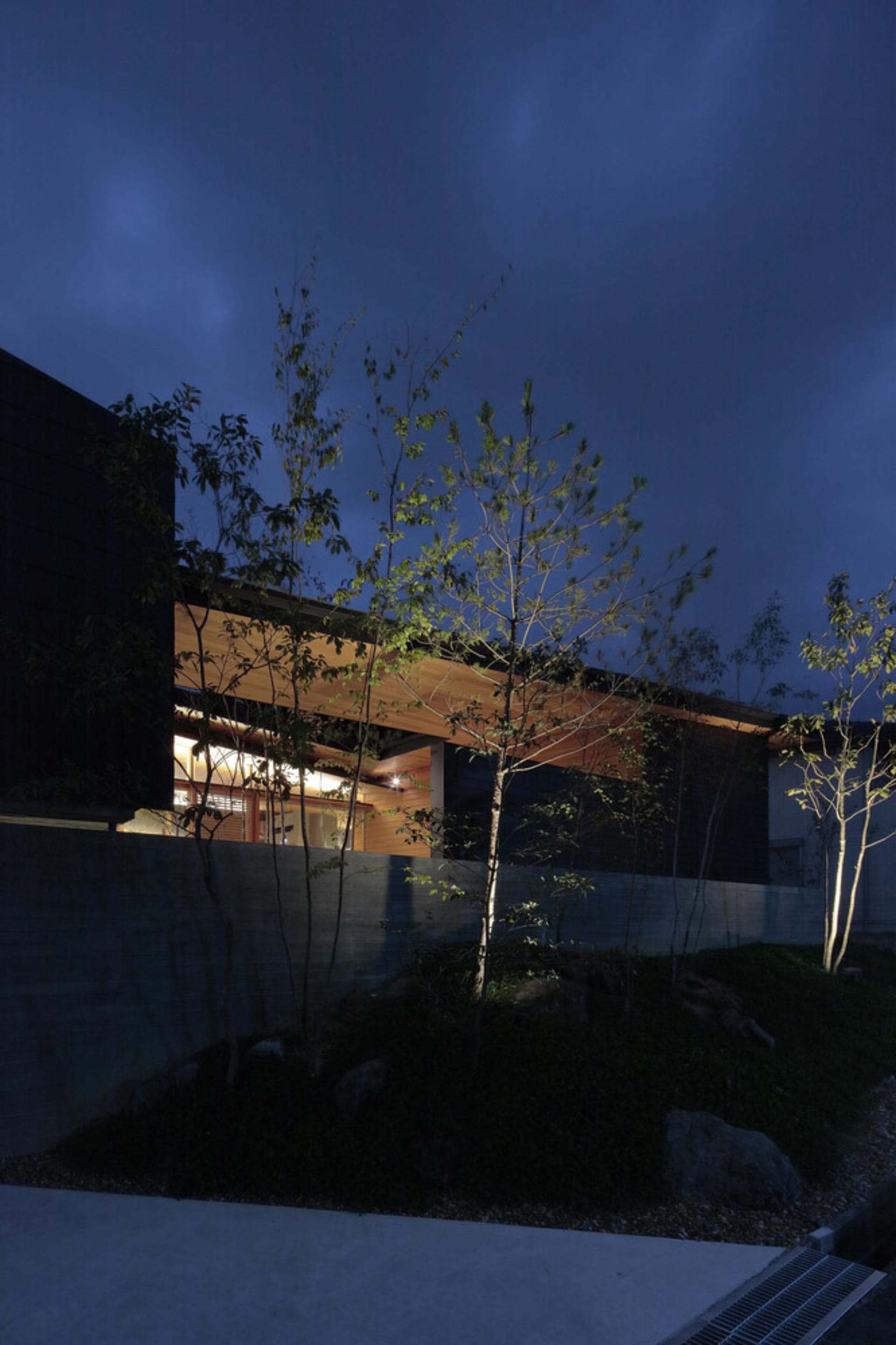 夜晚的現代極簡住宅,外牆採用混凝土與木質材料。
