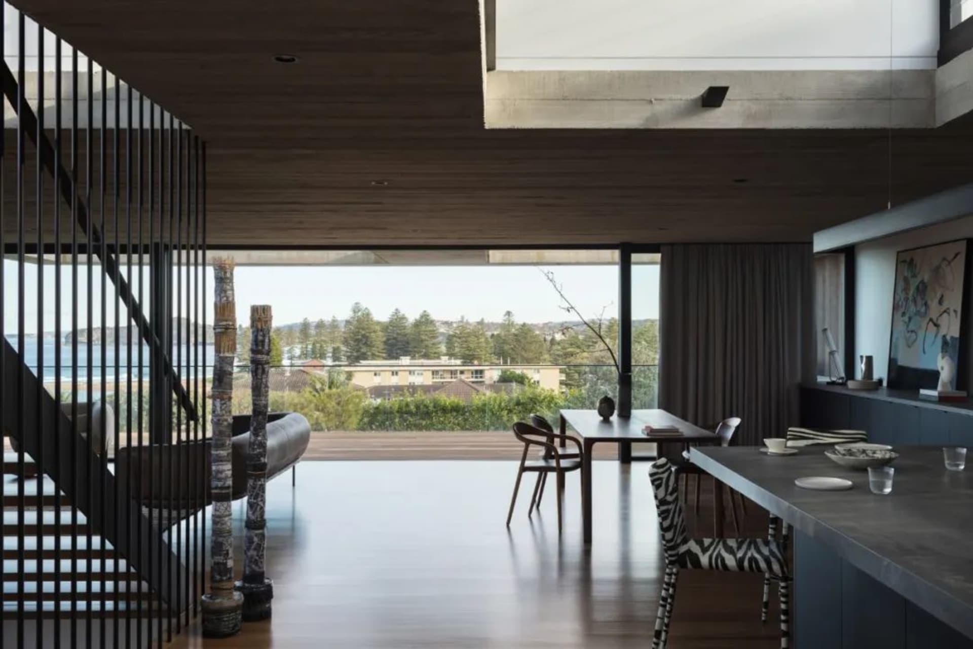 A modern living room featuring wooden flooring and furniture with a view of the surrounding landscape.
