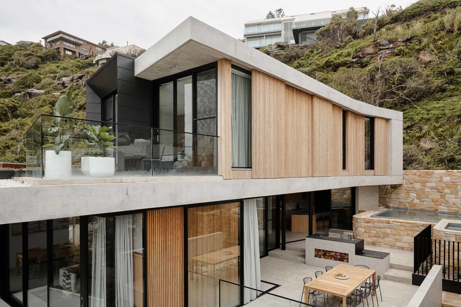Modern residential exterior featuring concrete, wood, and glass materials.