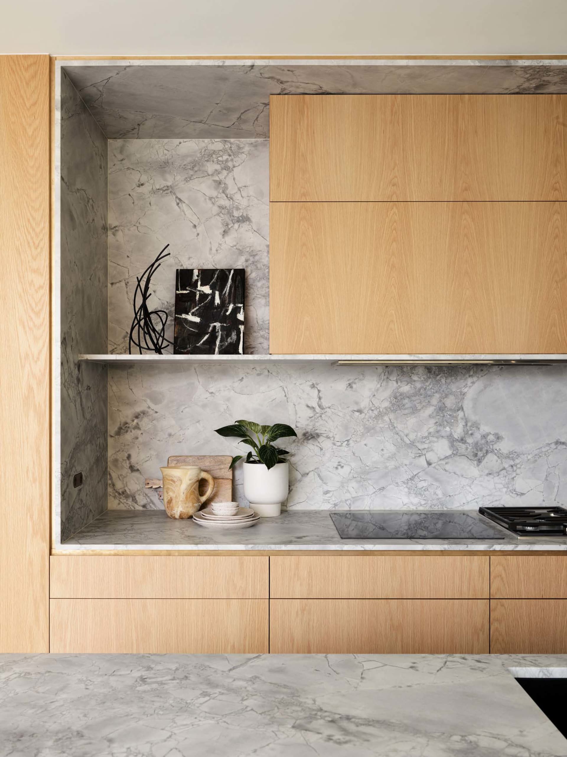 A minimalist residential kitchen featuring marble finishes and wooden cabinets.
