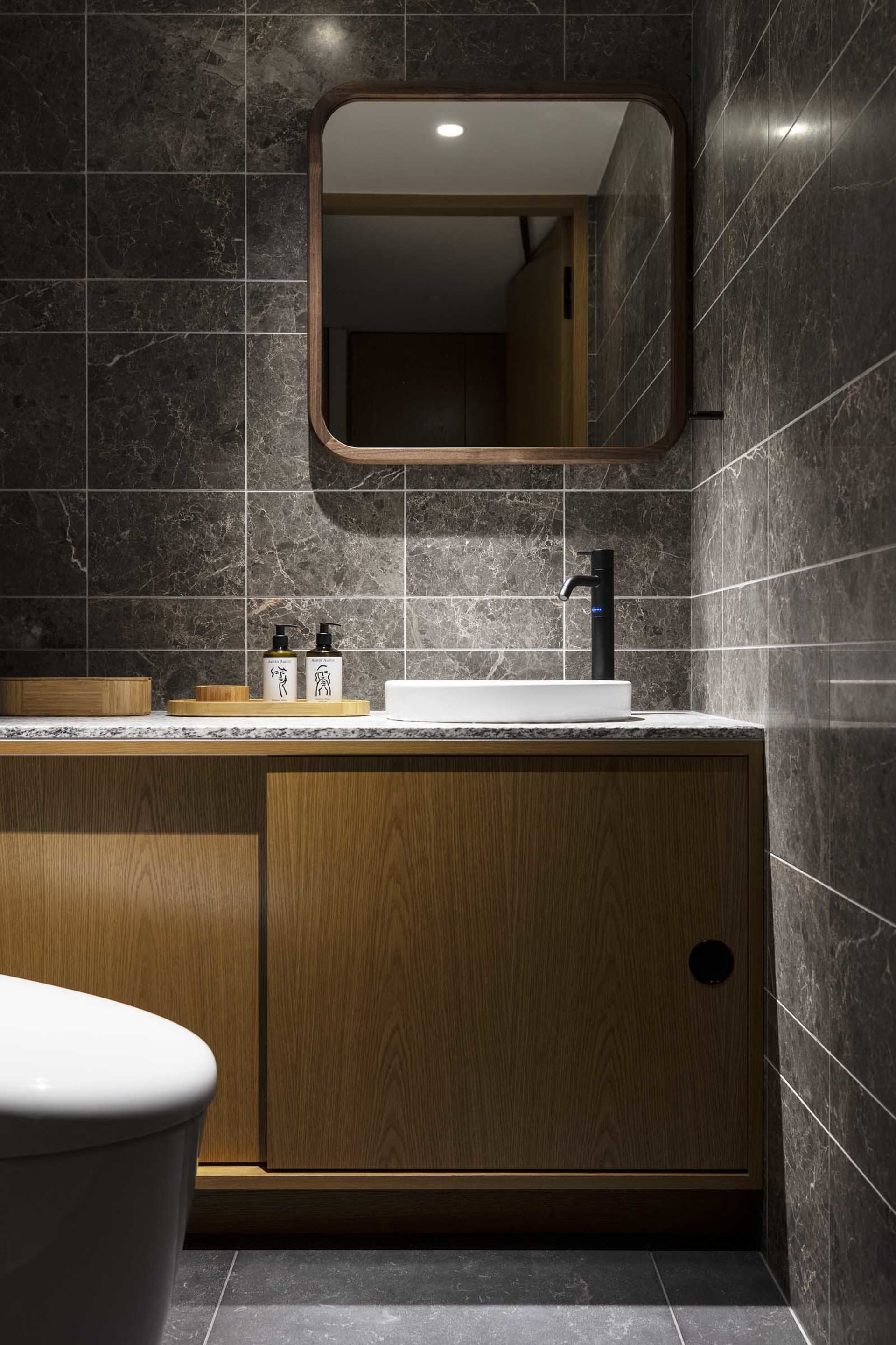 Modern bathroom with marble walls and wooden vanity.