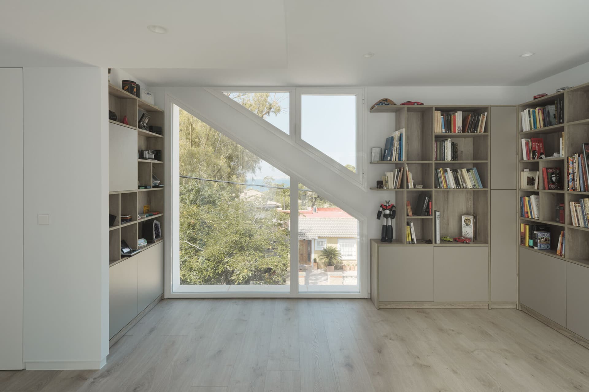 A modern living room featuring wooden shelves, floor-to-ceiling windows, and a minimalist design.
