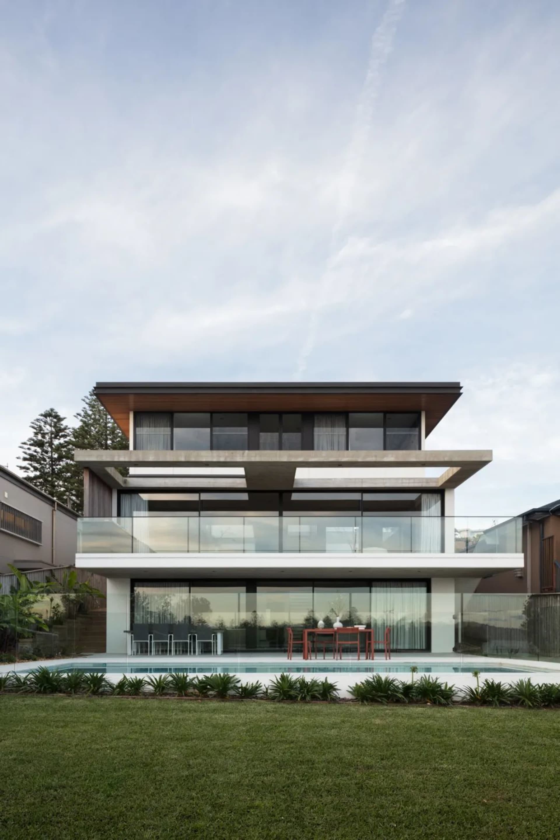 Two-story modern residential building with glass and concrete exterior materials