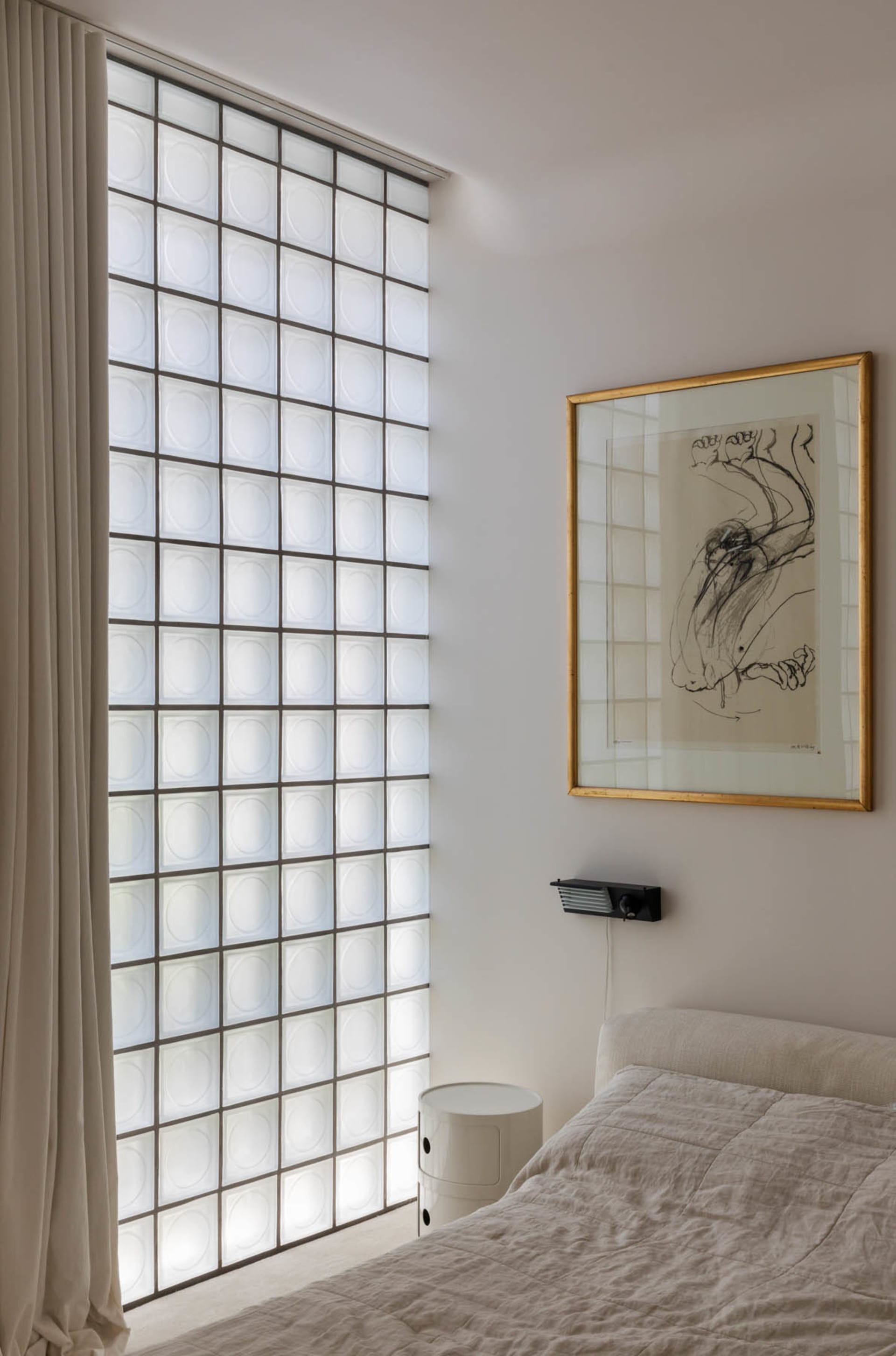 Bedroom with frosted glass block wall and minimalist decor.