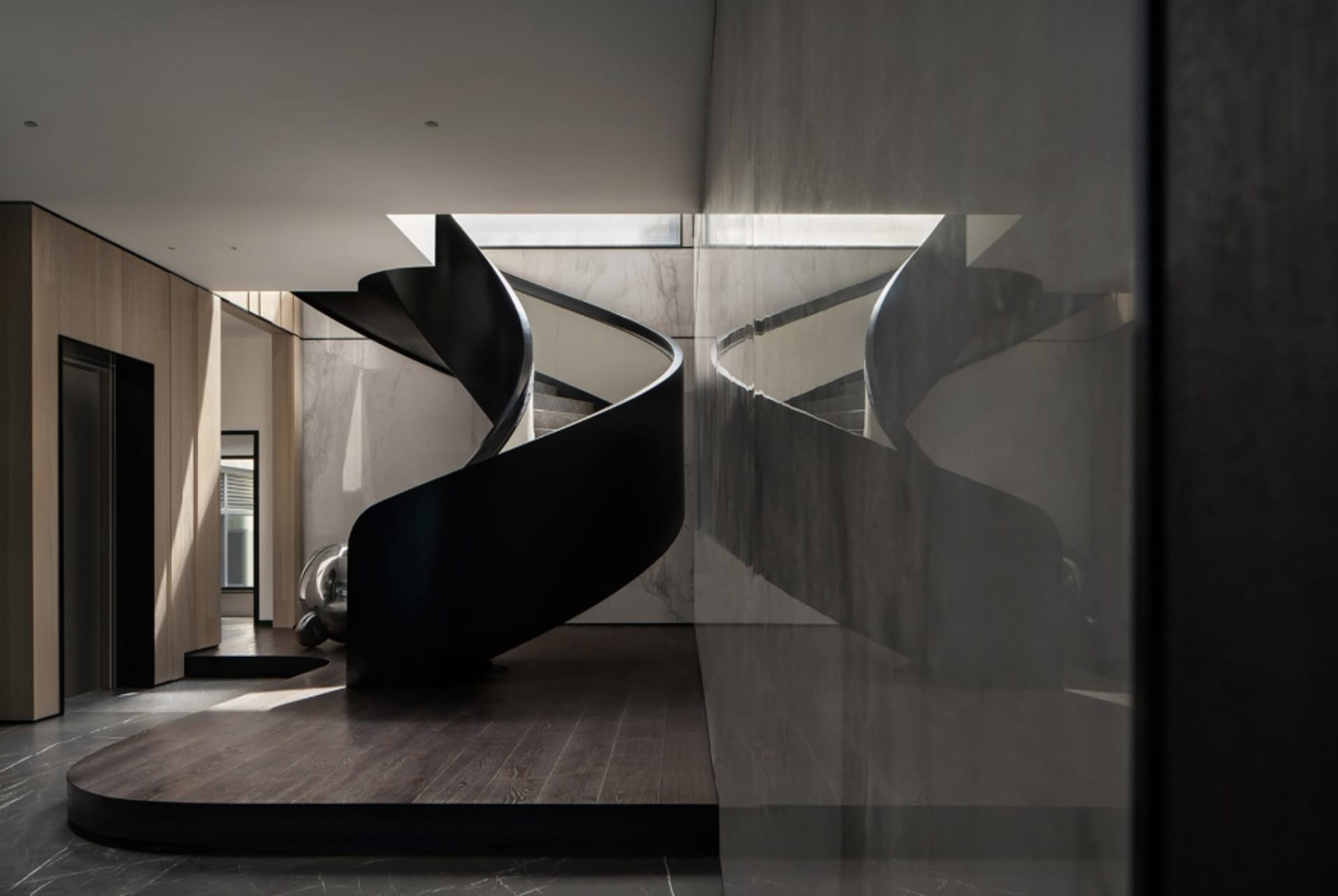 Modern black metal staircase with marble floor and glass walls.