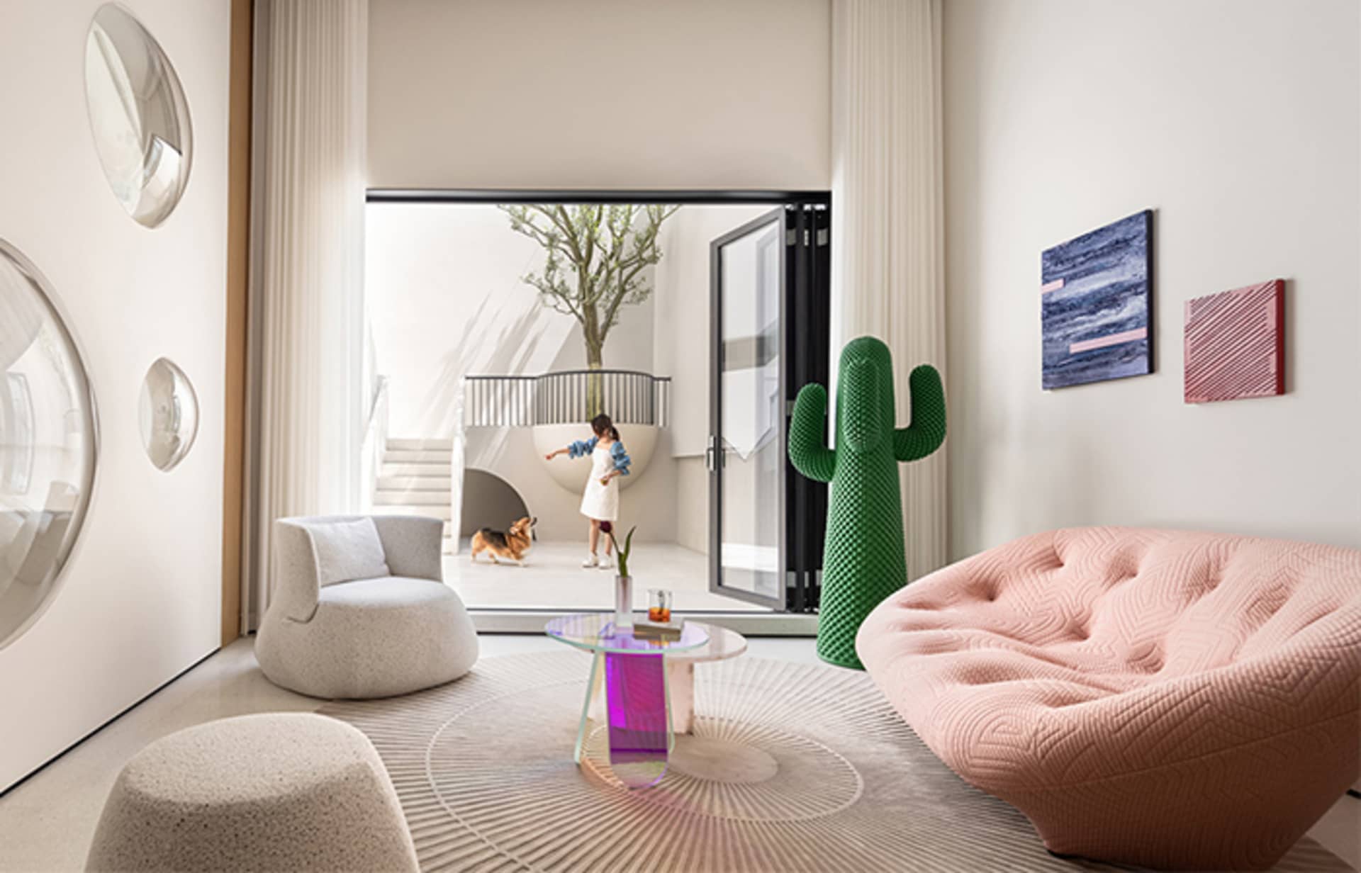 Modern living room with a white armchair, a pink couch, and a green cactus sculpture