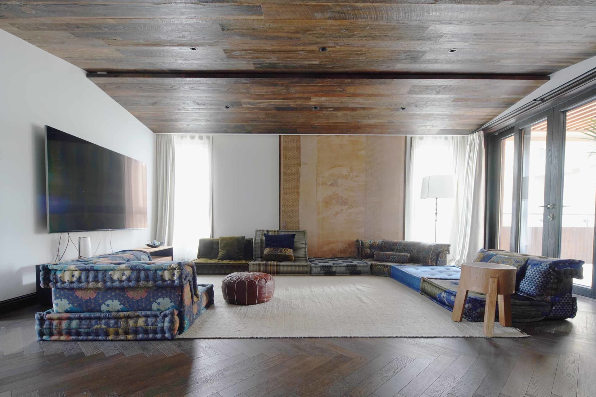 A modern living room with a wooden floor, ceiling, and furniture.