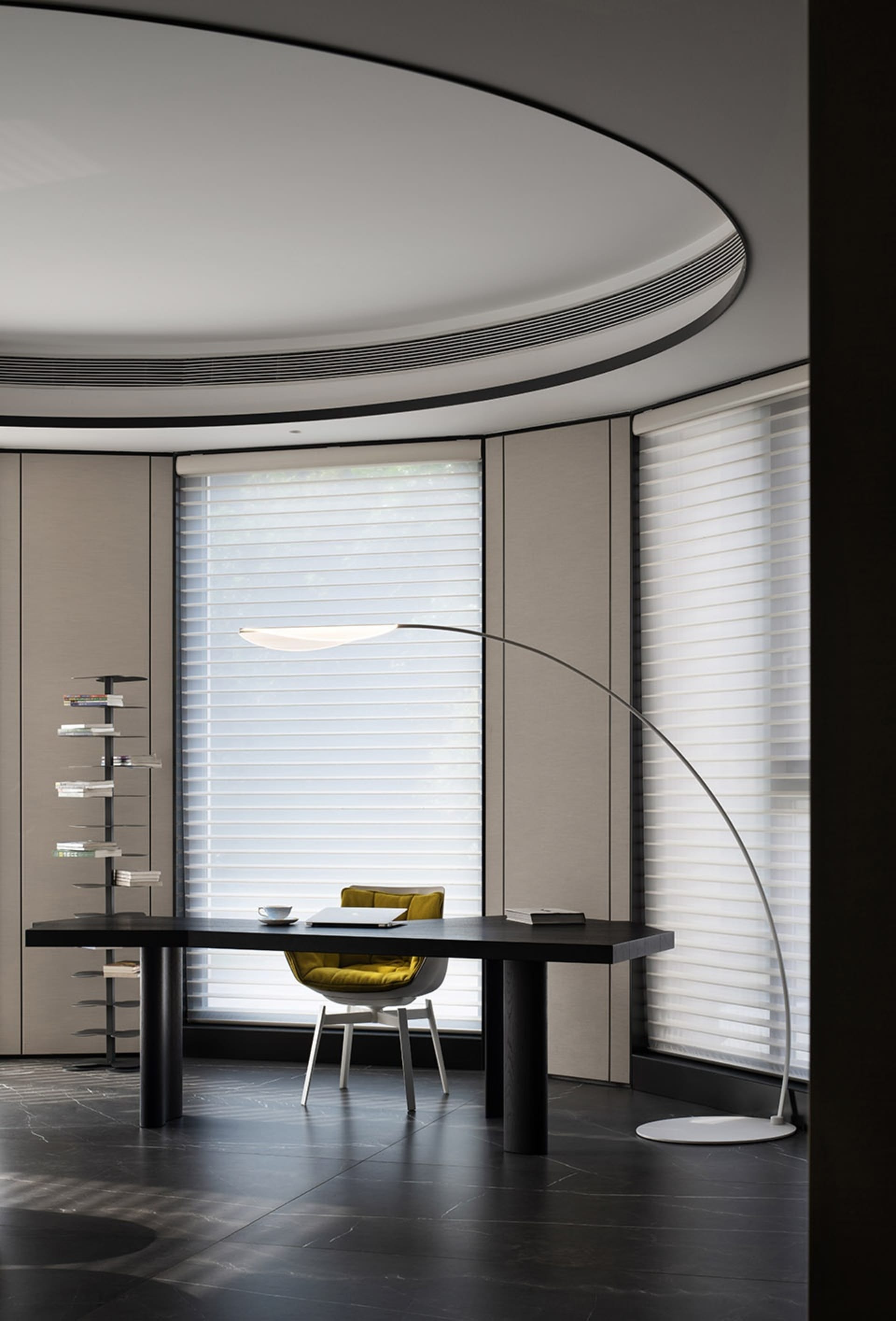 A modern office desk with a sleek design, minimalistic style, and a large window with blinds.