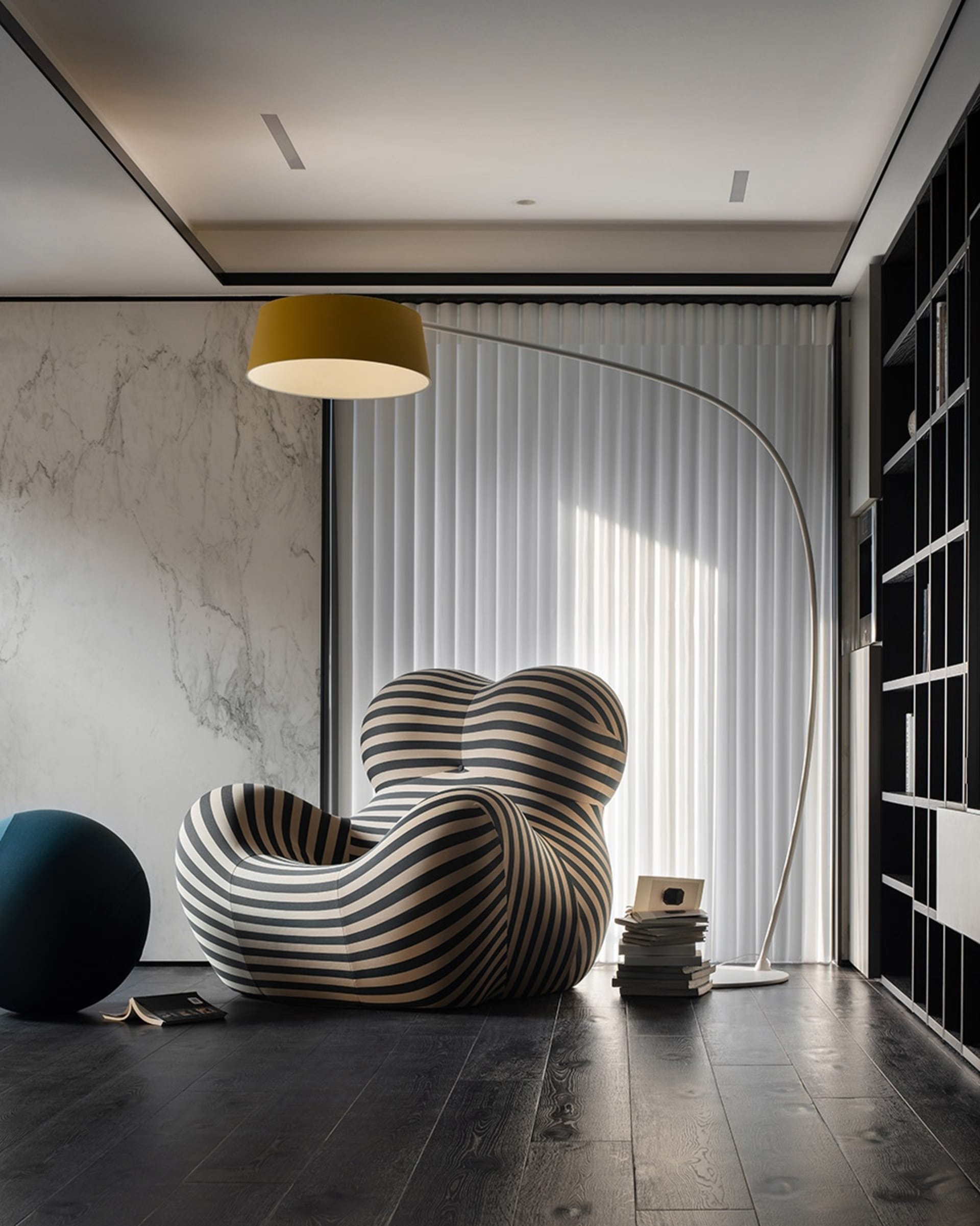 A modern living room featuring a unique, textured armchair and a sleek, floor-standing lamp.