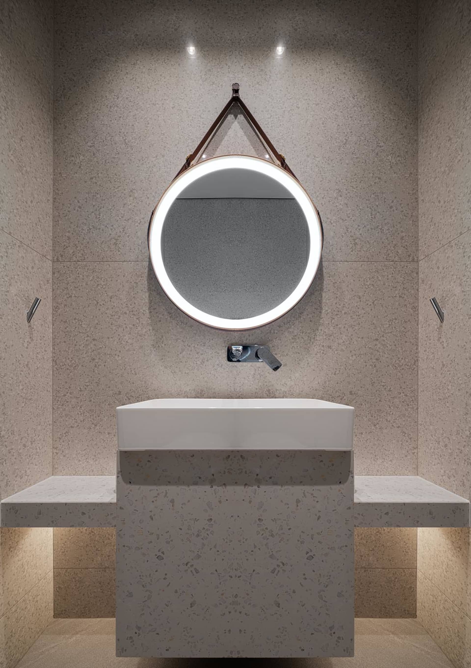 A minimalist bathroom featuring a terrazzo sink and wall-mounted fixtures.