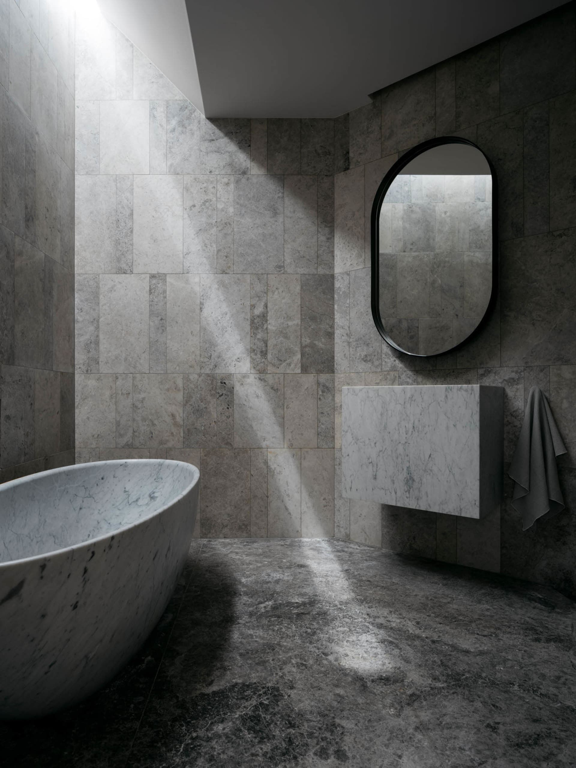 A modern minimalist bathroom with marble walls and floor, featuring a freestanding bathtub and a floating vanity.