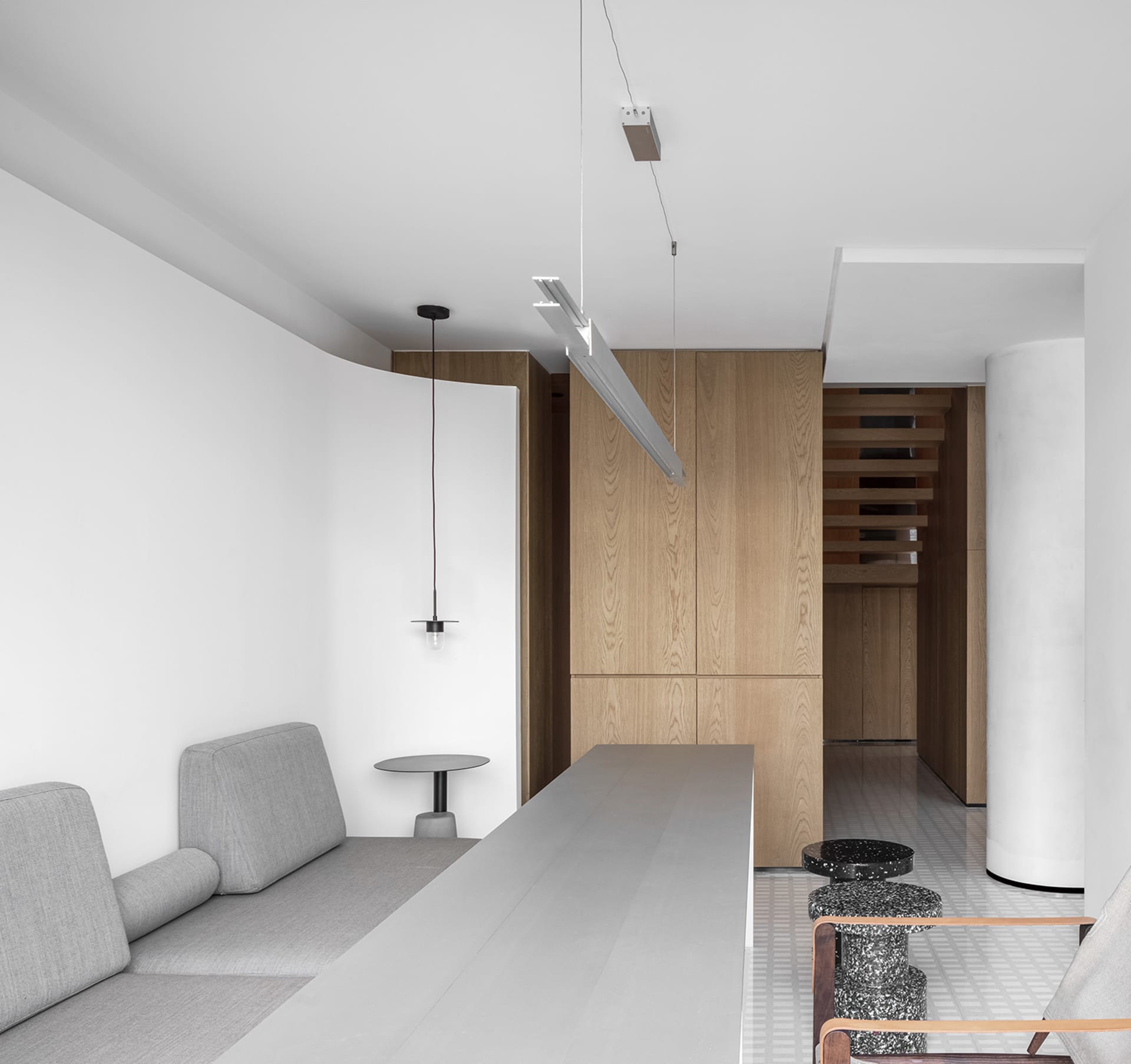 Modern living room with concrete walls, wooden furniture, and minimalistic decor.