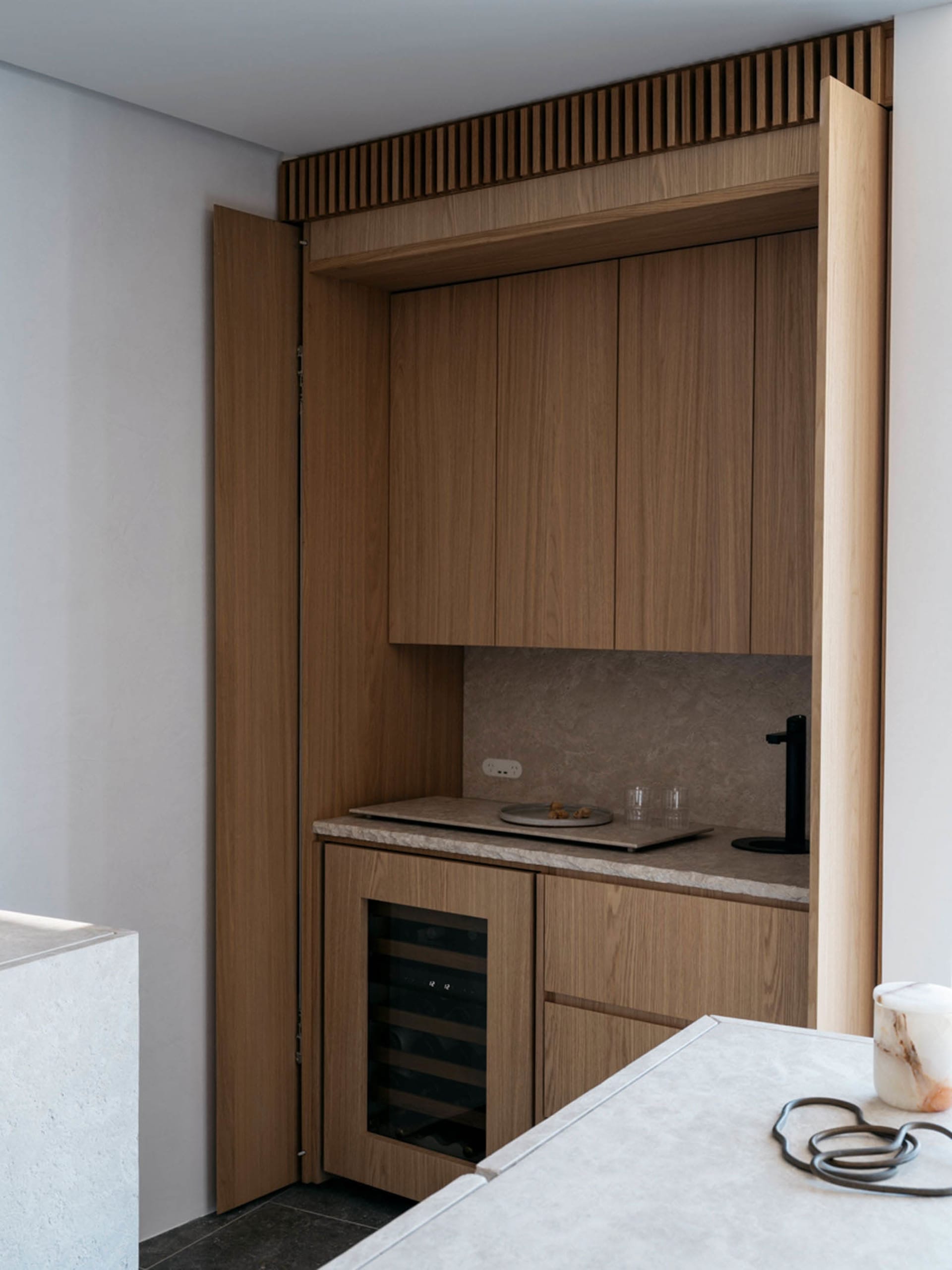 Modern minimalist kitchen featuring wood cabinetry and countertop.