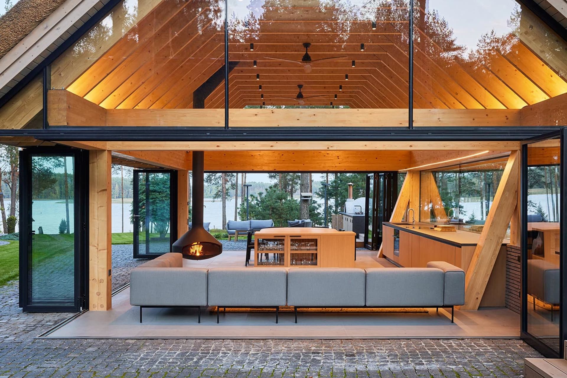 Modern residential interior with a wooden architecture and furnishings, featuring a lounge area with a fireplace and an open