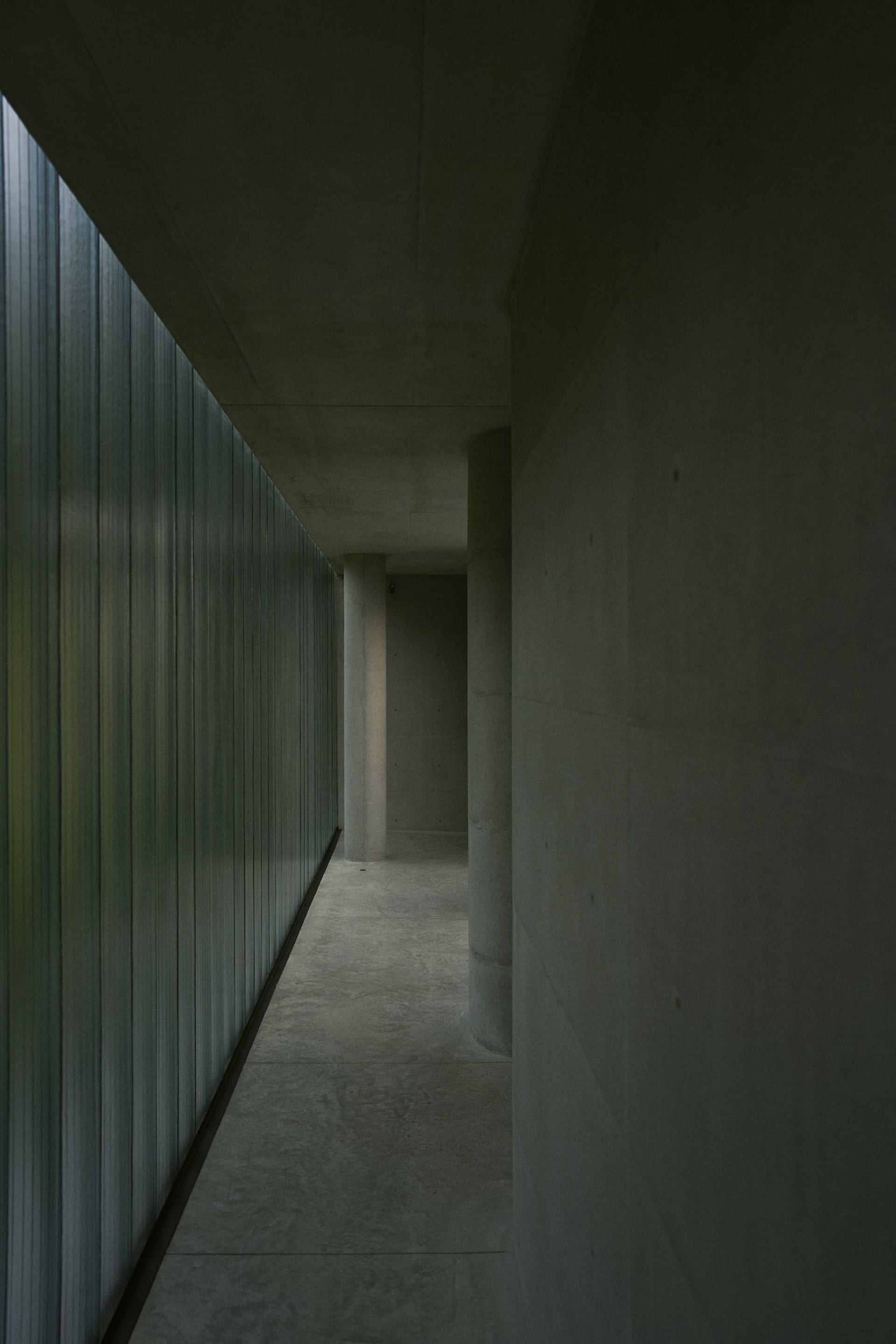 Minimalist design corridor featuring concrete and glass materials.