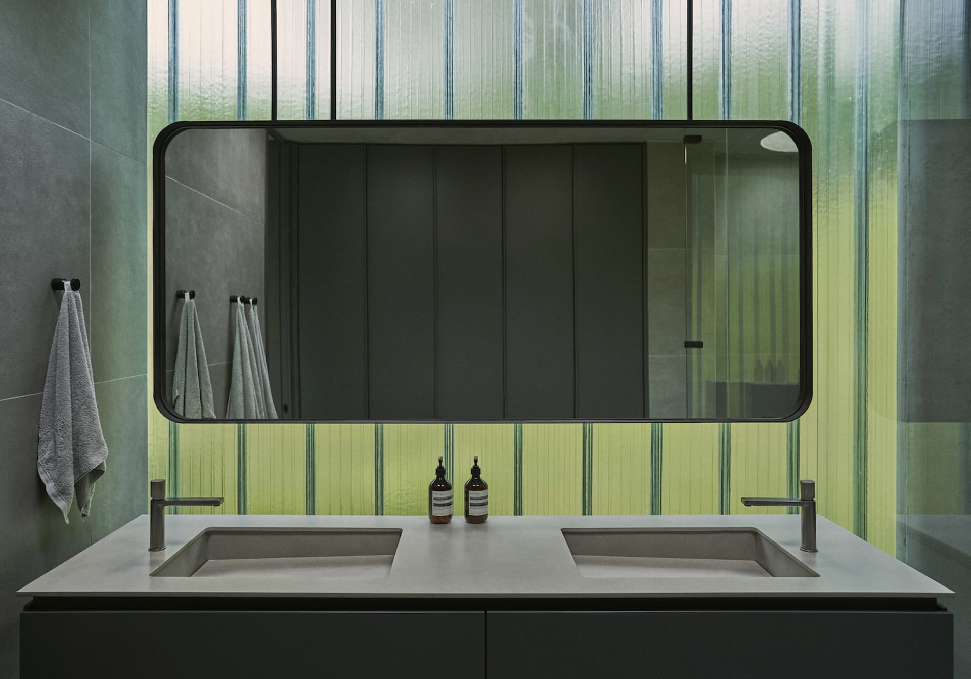 A sleek modern bathroom with concrete countertops, a glass shower enclosure, and minimalist design.
