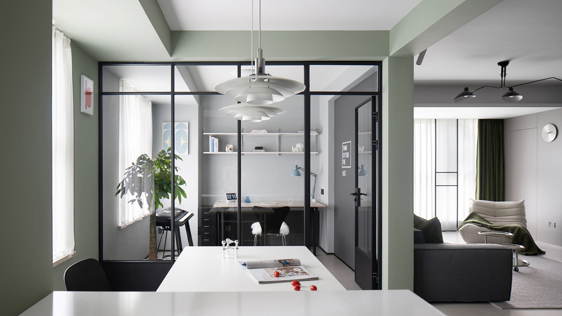 A modern living, dining, and office space featuring glass walls, cement flooring, and contemporary furniture.