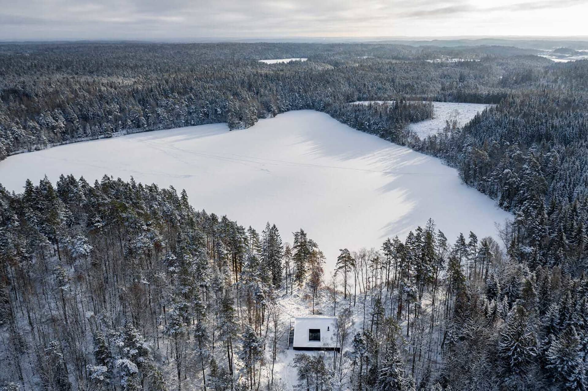 極簡風度假小屋隱身於雪覆樹林與結冰湖泊之間。